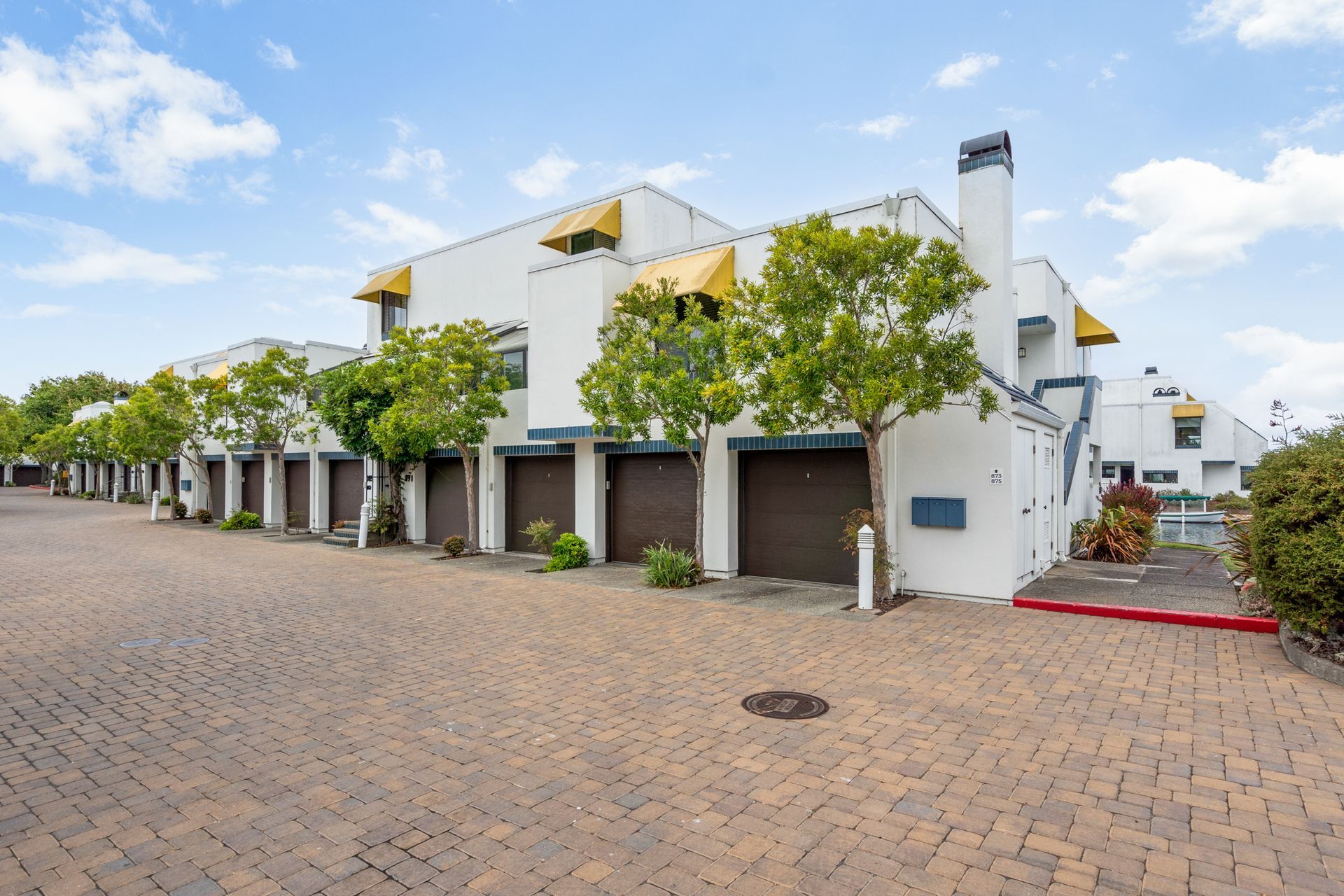 A white building with a lot of garages and trees in front of it