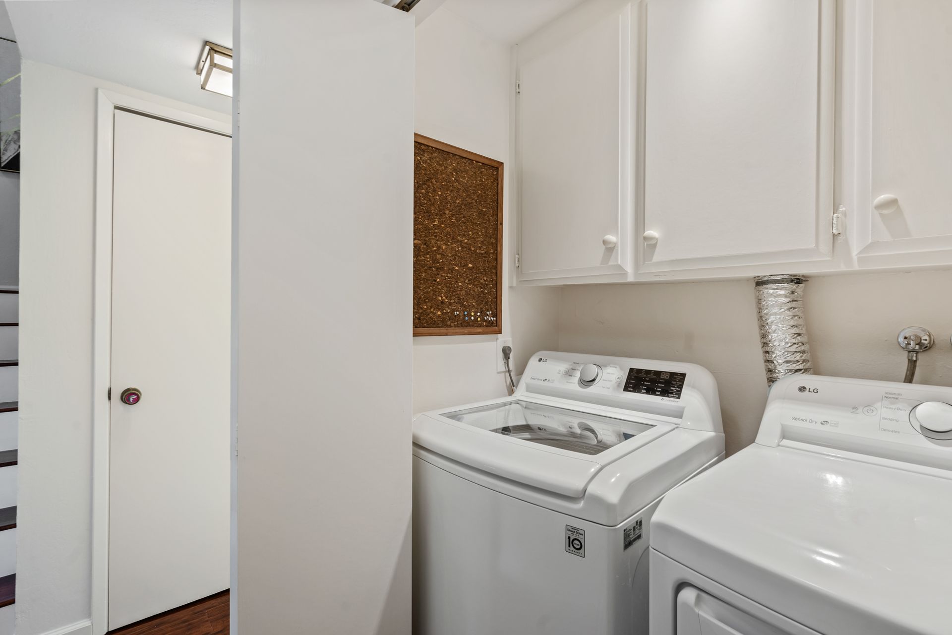 A laundry room with a washer and dryer and white cabinets.