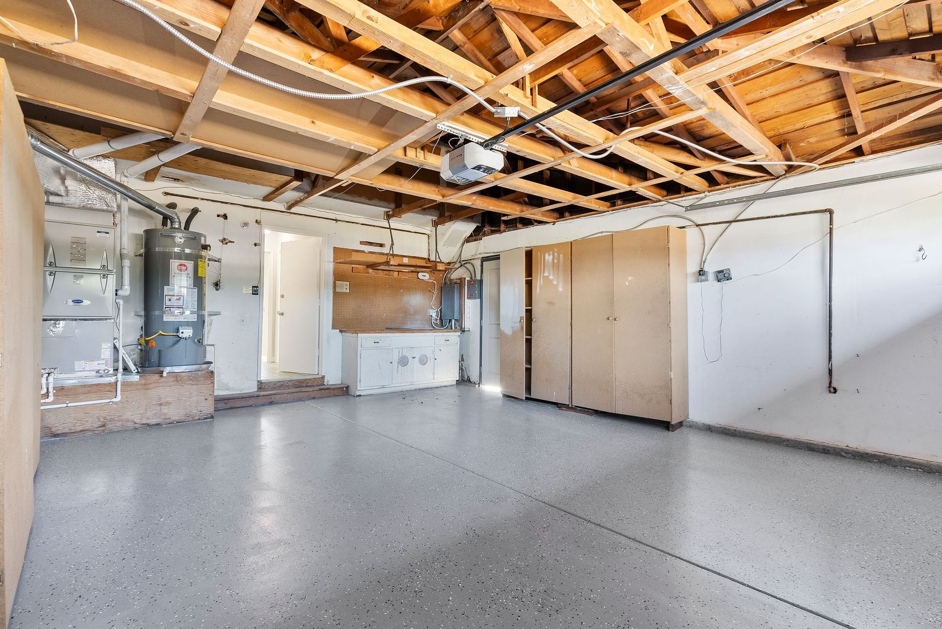 An empty garage with a wooden ceiling and a gray floor.