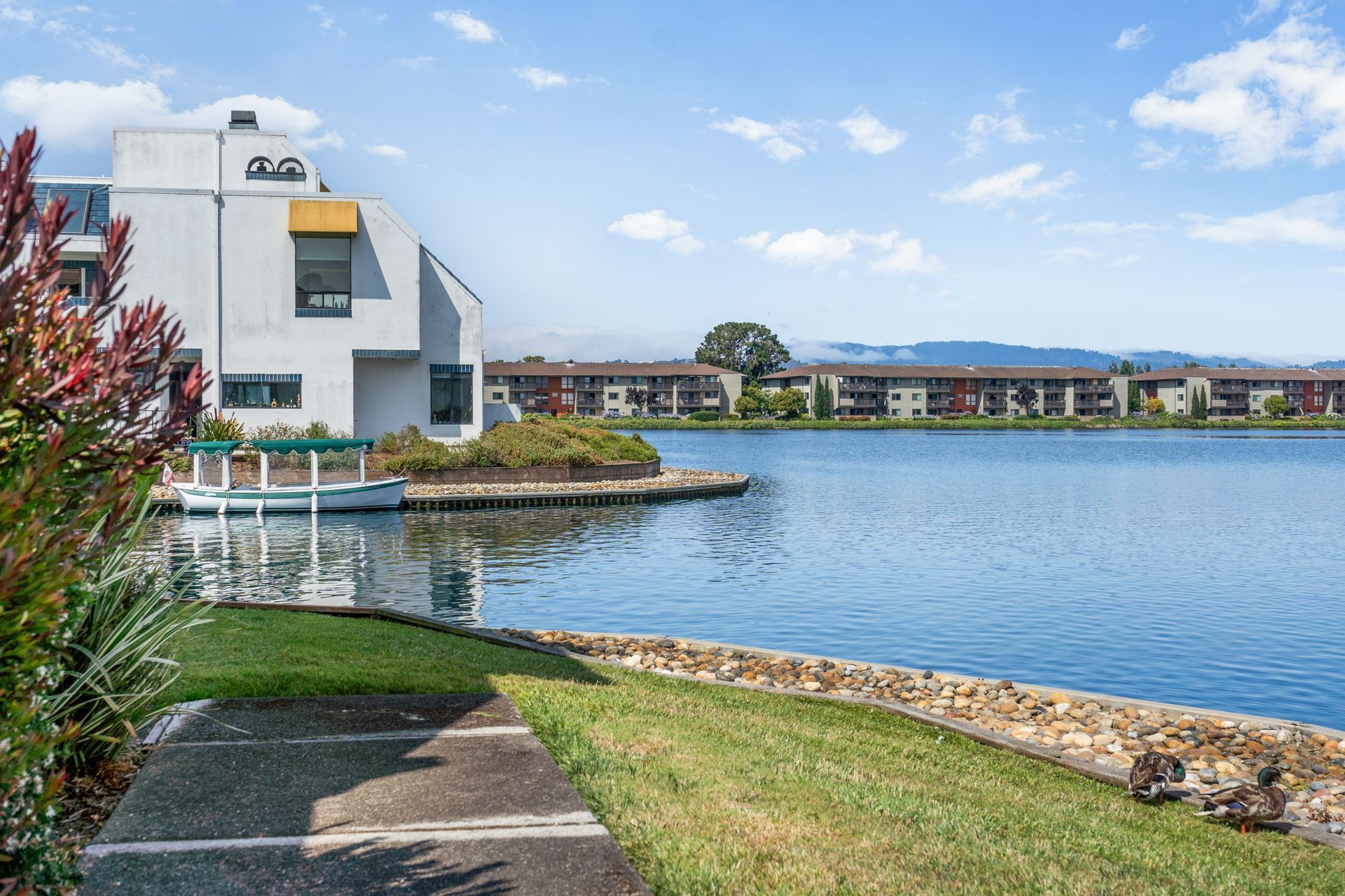A large white house is sitting next to a large body of water.