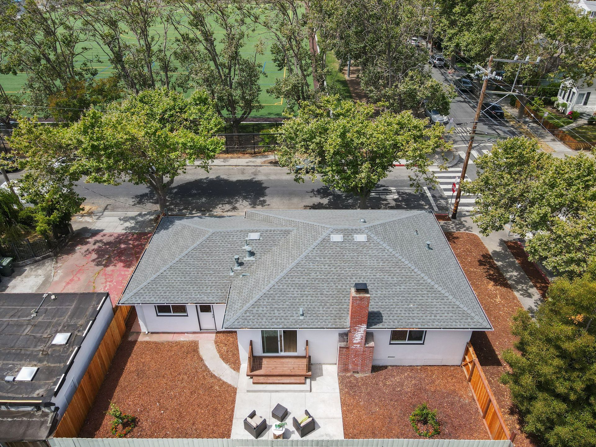 An aerial view of a house with a soccer field in the background