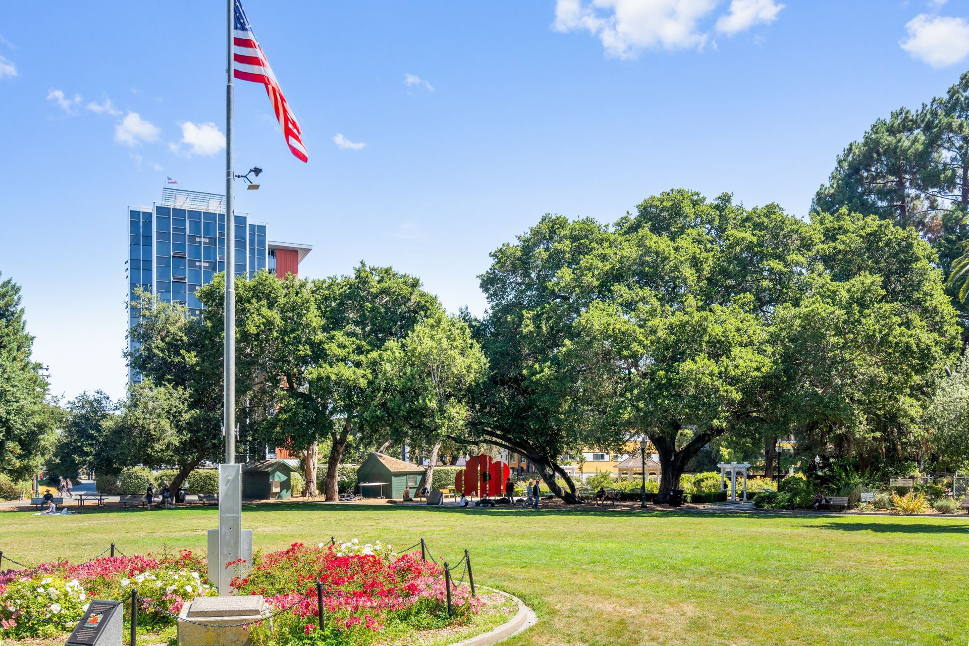 An american flag is flying in a park with trees in the background.