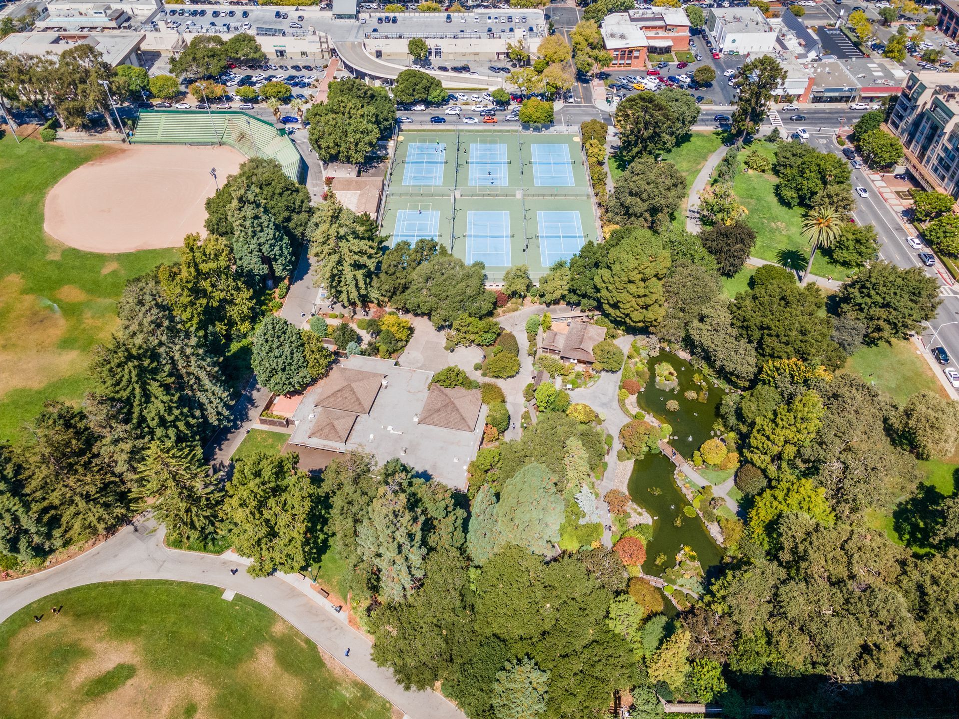 An aerial view of a park with tennis courts and a baseball field