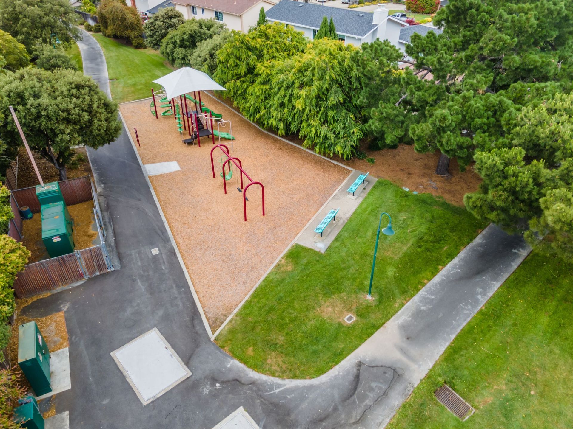 An aerial view of a playground in a park surrounded by trees.