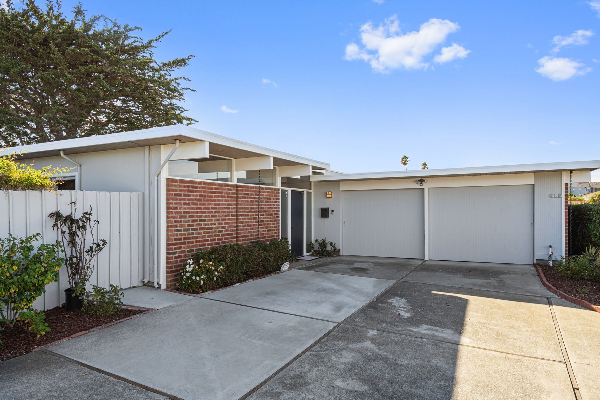 A white house with two garages and a brick wall