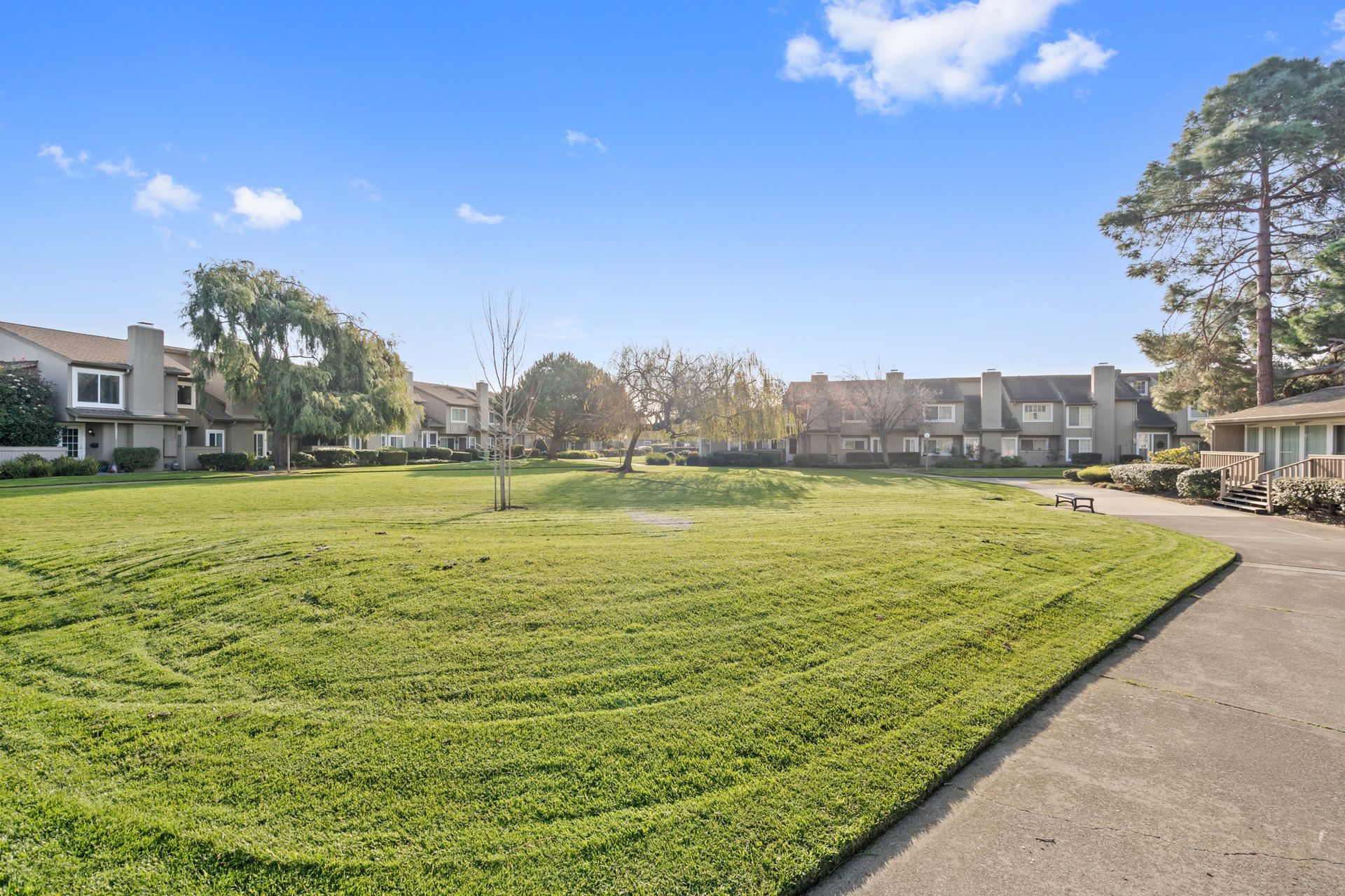 There is a large grassy field in the middle of a residential area.