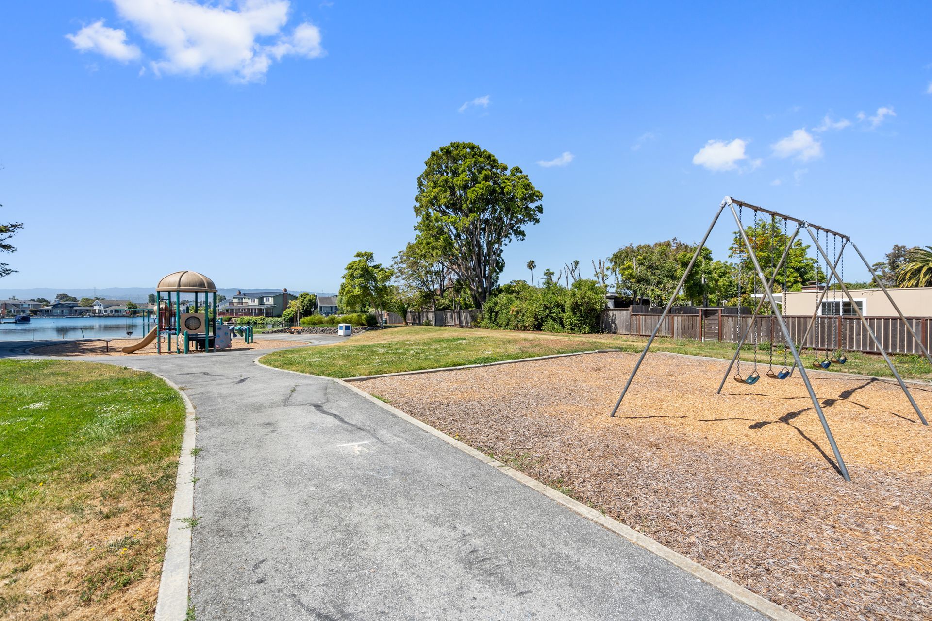 A playground with a swing set and a path leading to it.