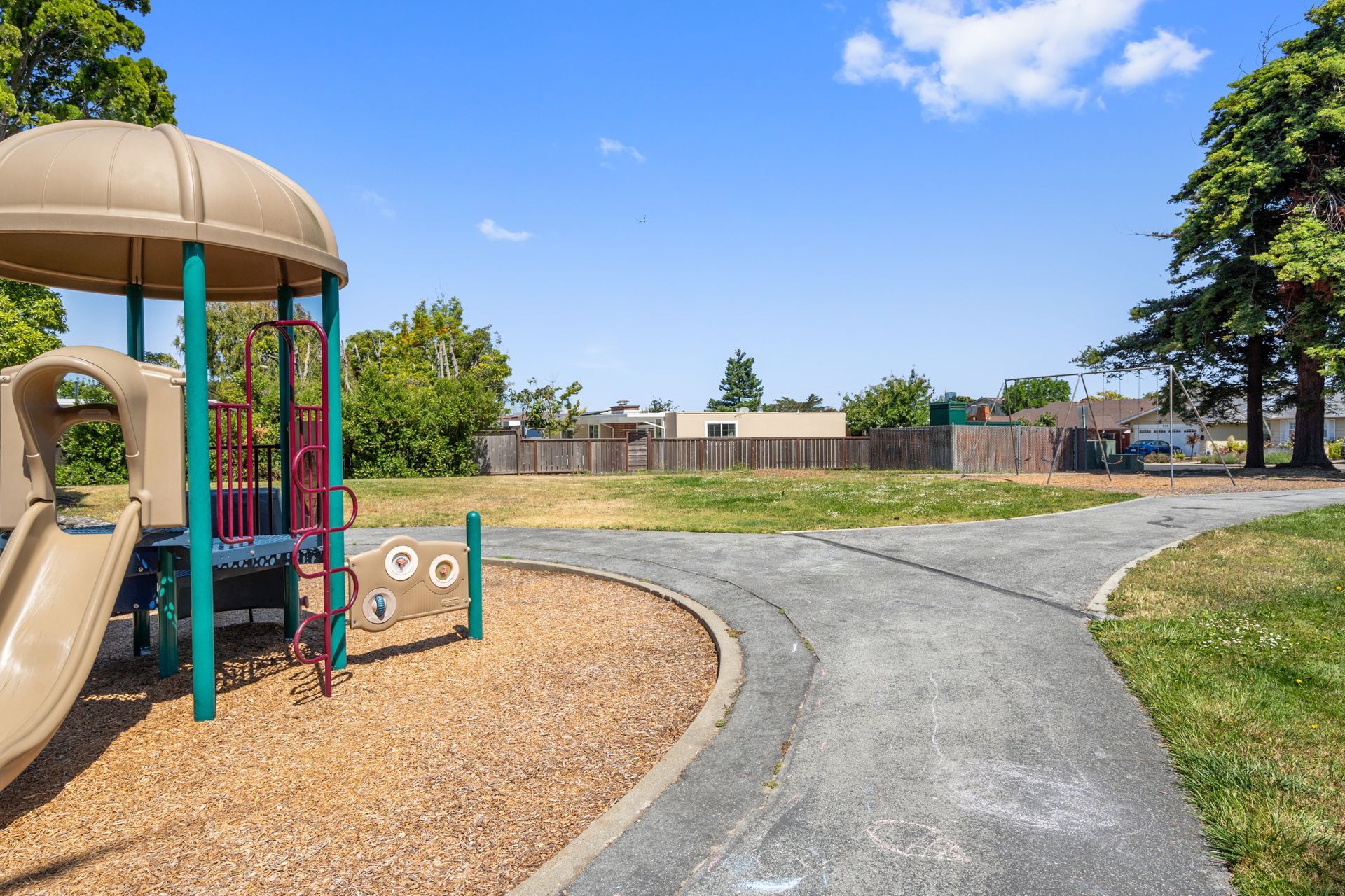 A playground with a slide and a path in a park.