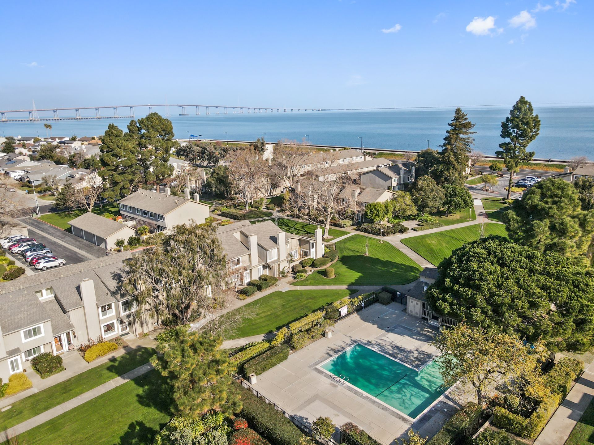 An aerial view of a residential area with a swimming pool and a view of the ocean.