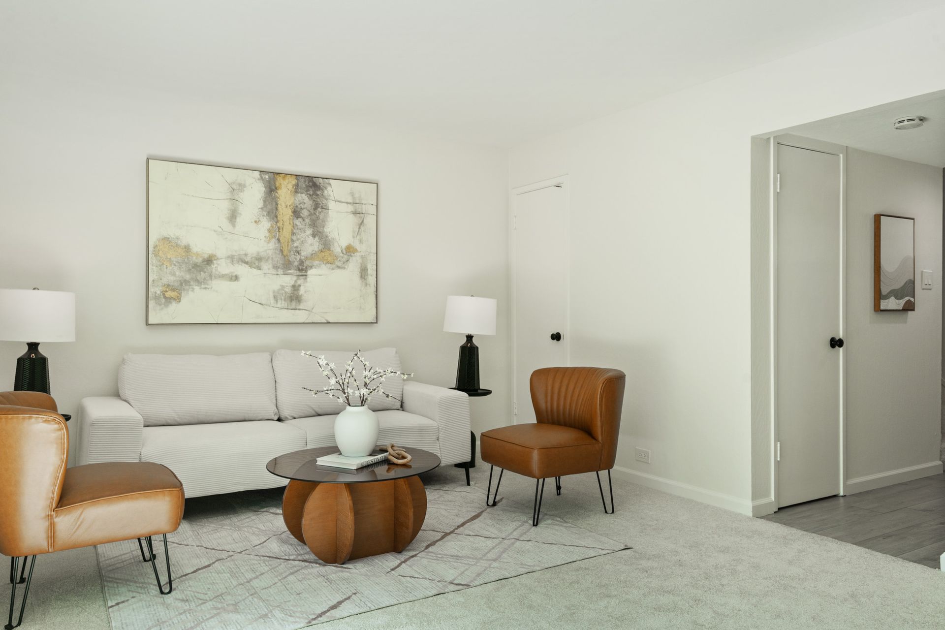 A living room with a couch , two chairs , a coffee table and a painting on the wall.