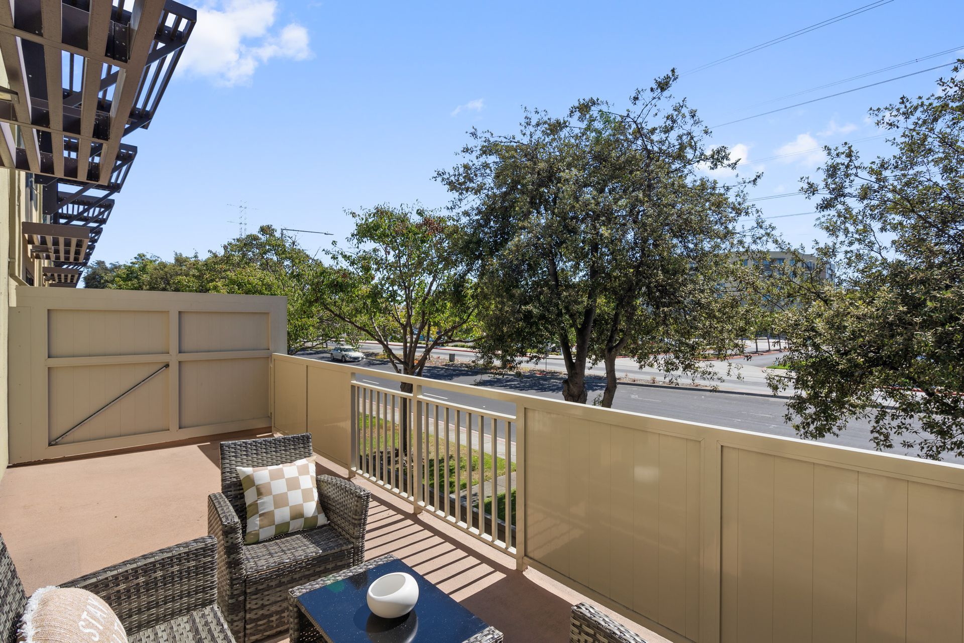 A balcony with wicker chairs and a coffee table with a view of a city.