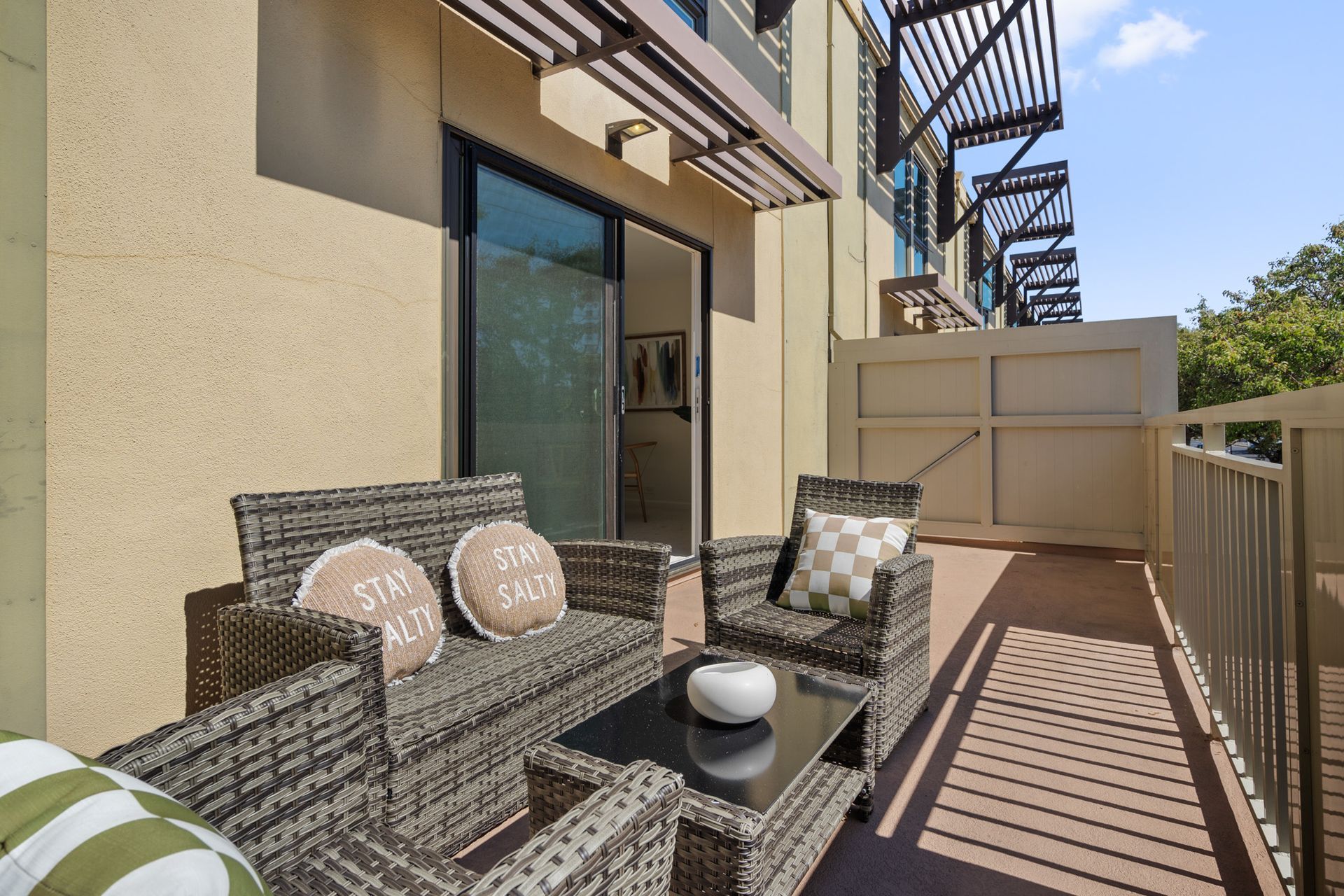 A balcony with wicker furniture and a fire escape