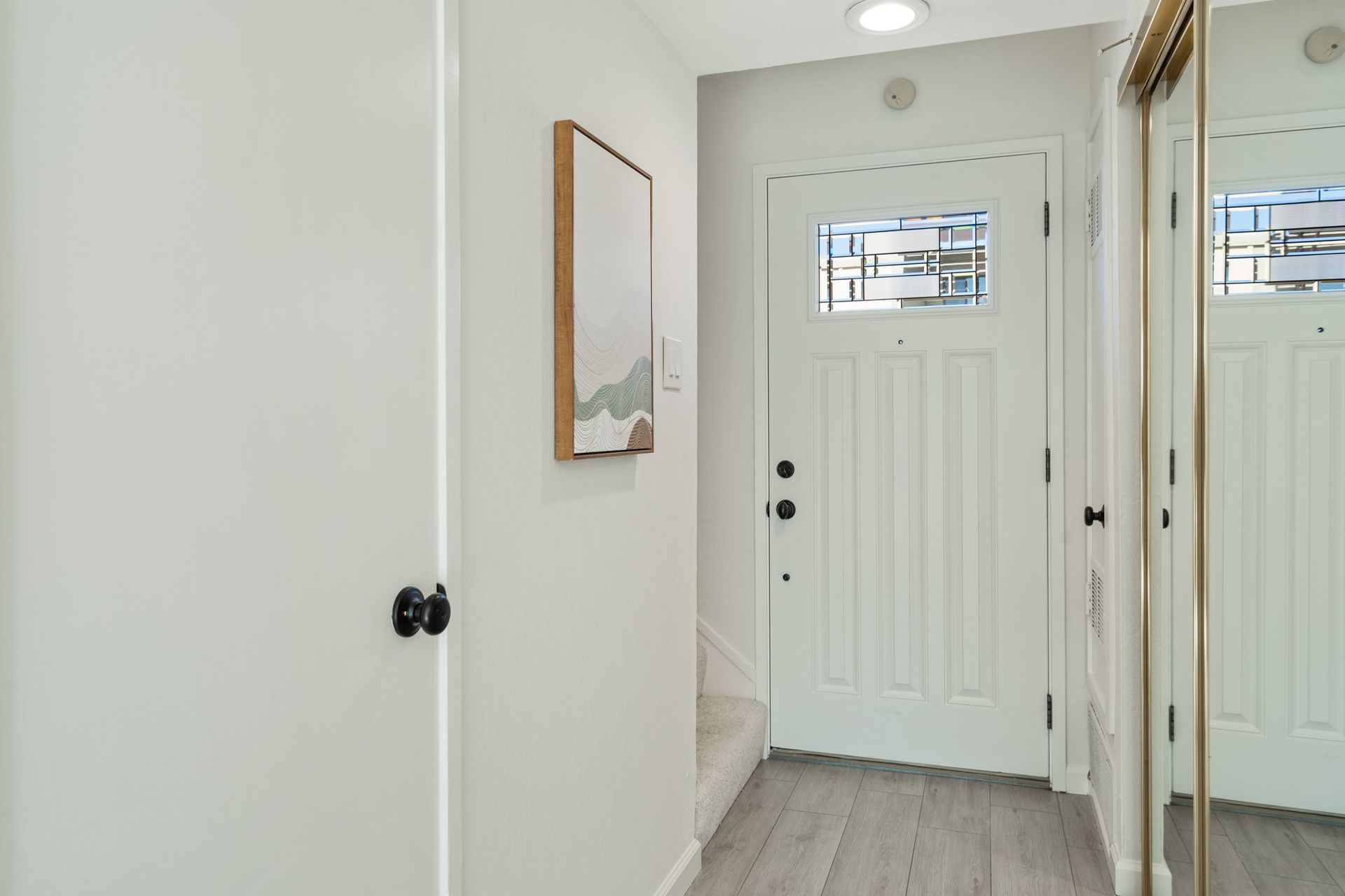 A hallway with a white door and a mirror.