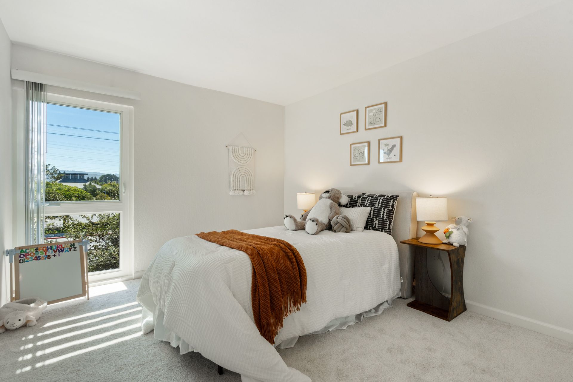 A bedroom with a bed , nightstand , lamps and a window.