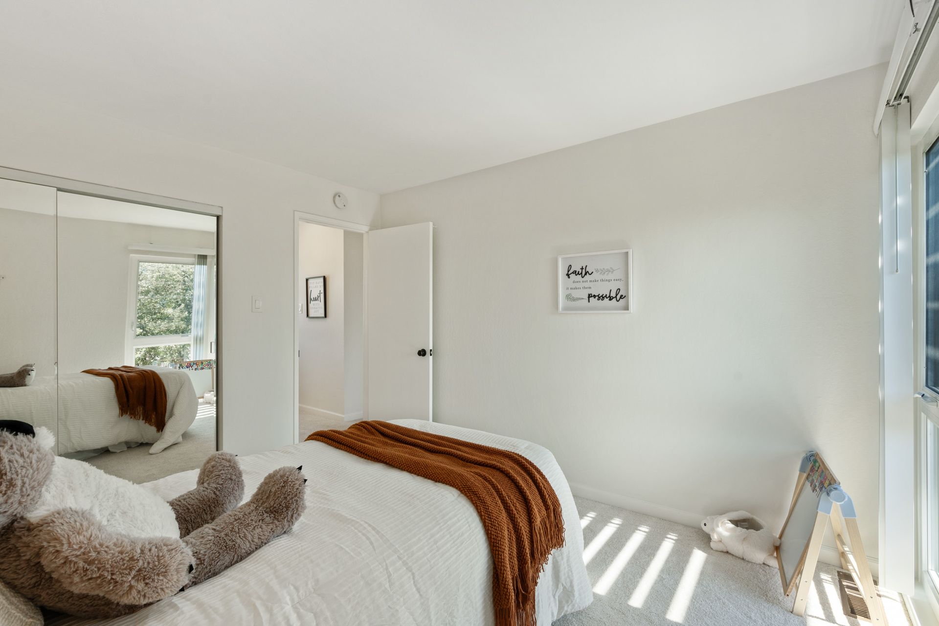 A bedroom with a bed and a teddy bear on it.