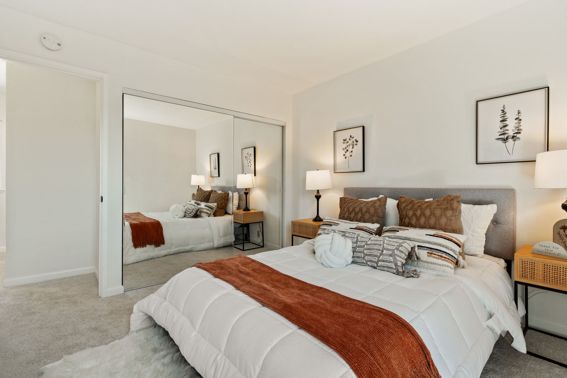 A bedroom with a large bed and a mirrored closet.