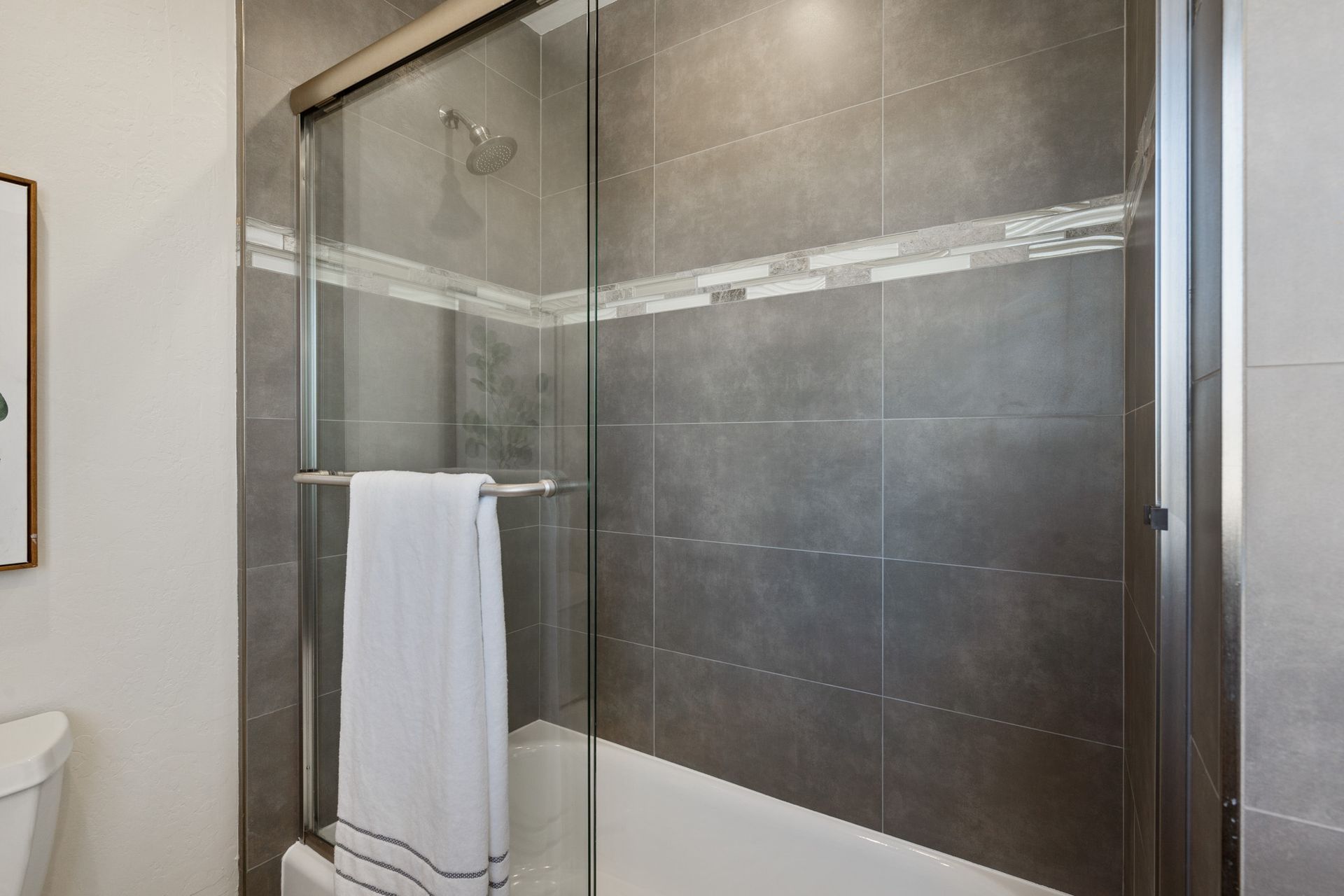 A bathroom with a sliding glass shower door and a bathtub.