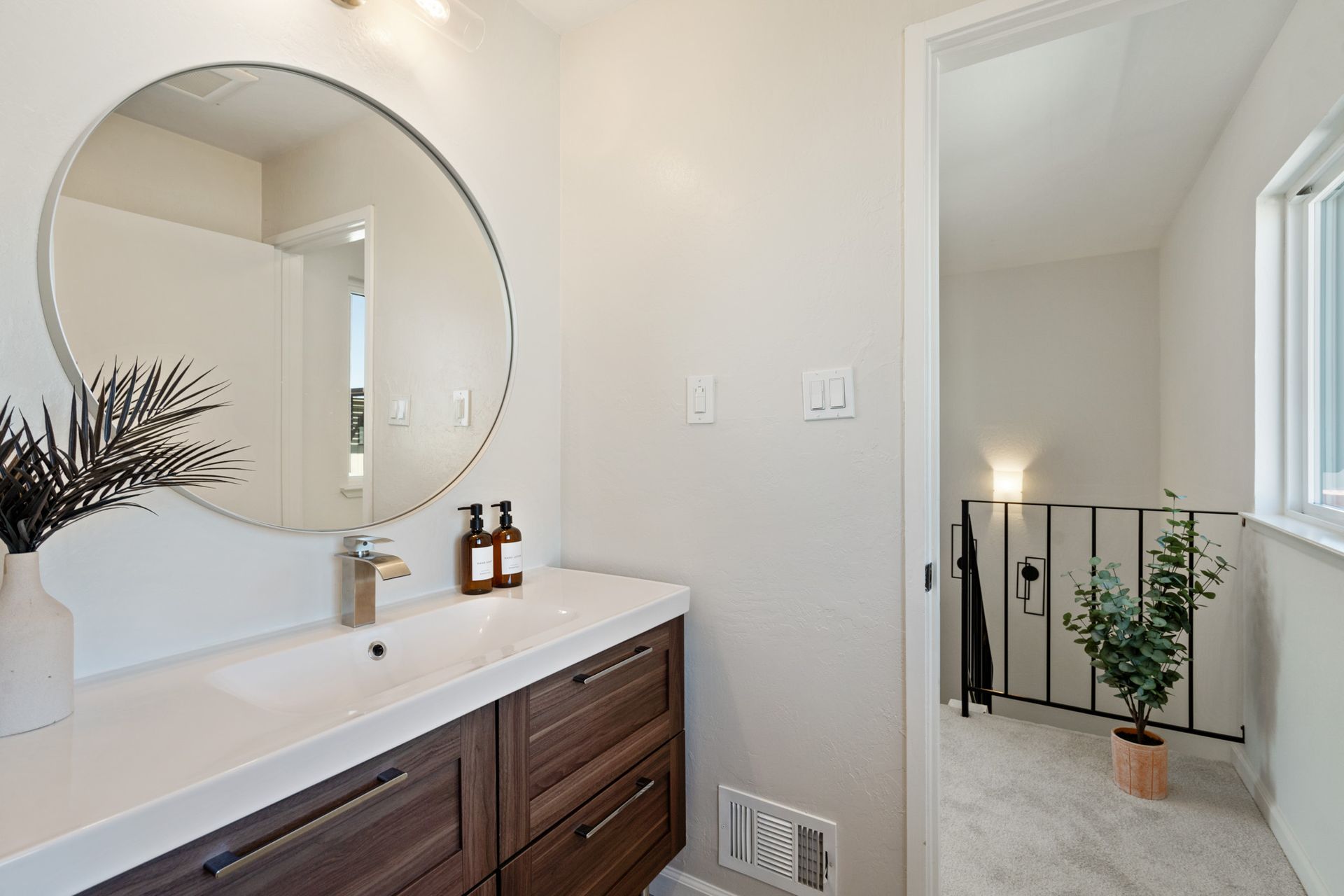 A bathroom with a sink and a round mirror.