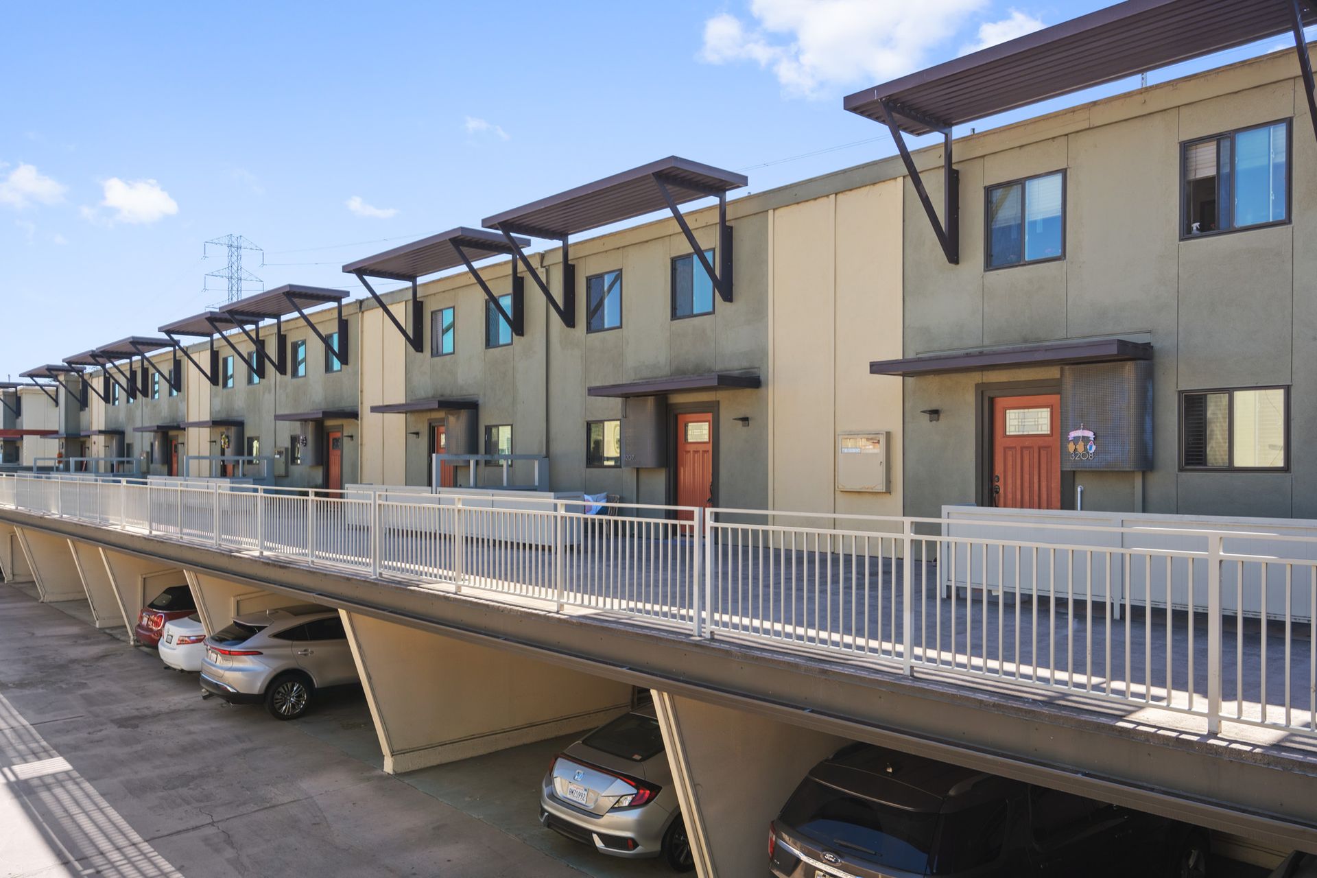 A row of apartment buildings with cars parked underneath them.