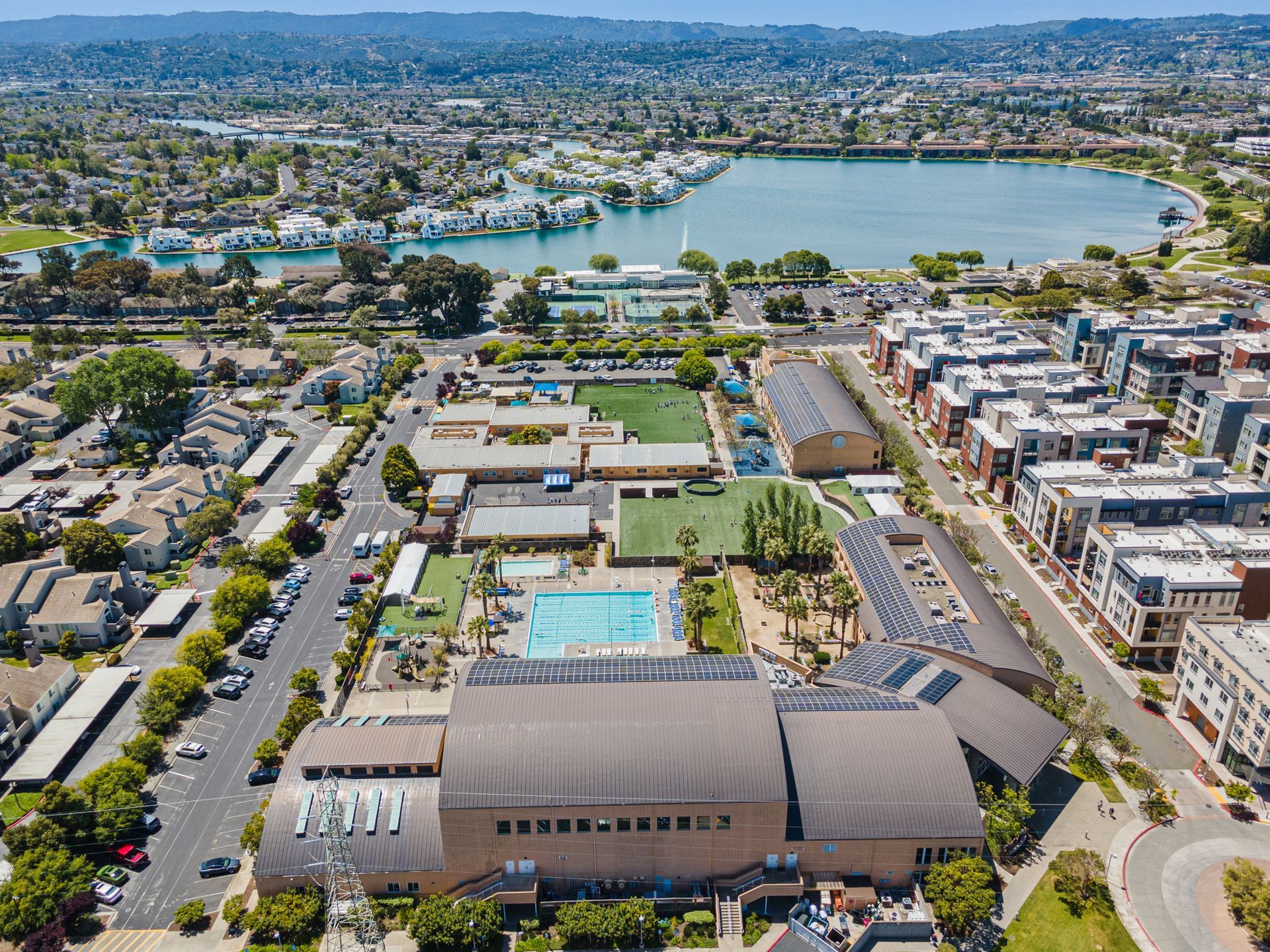 An aerial view of a large building with a pool in the middle of a city.