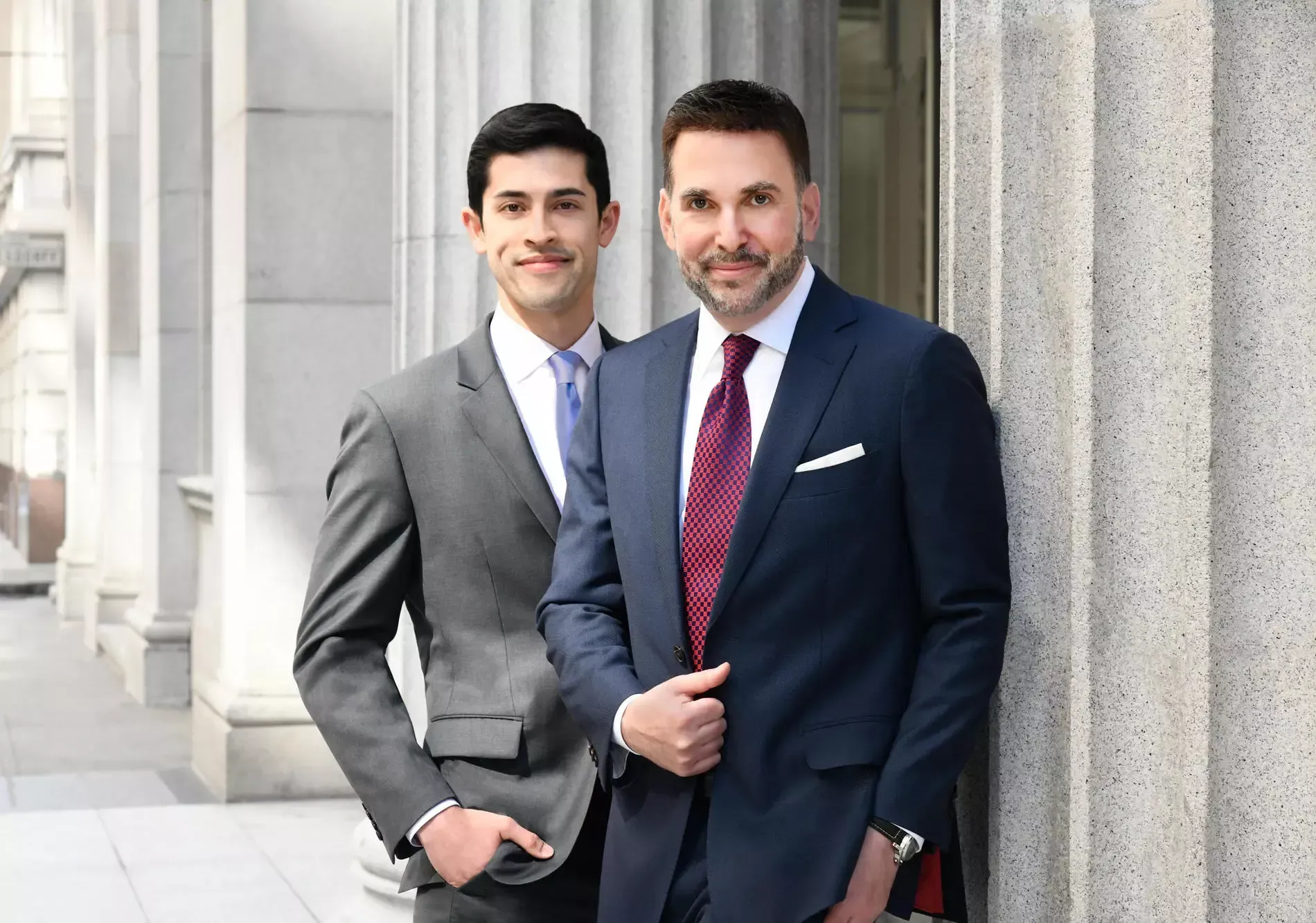 Two men in suits and ties are standing next to each other.