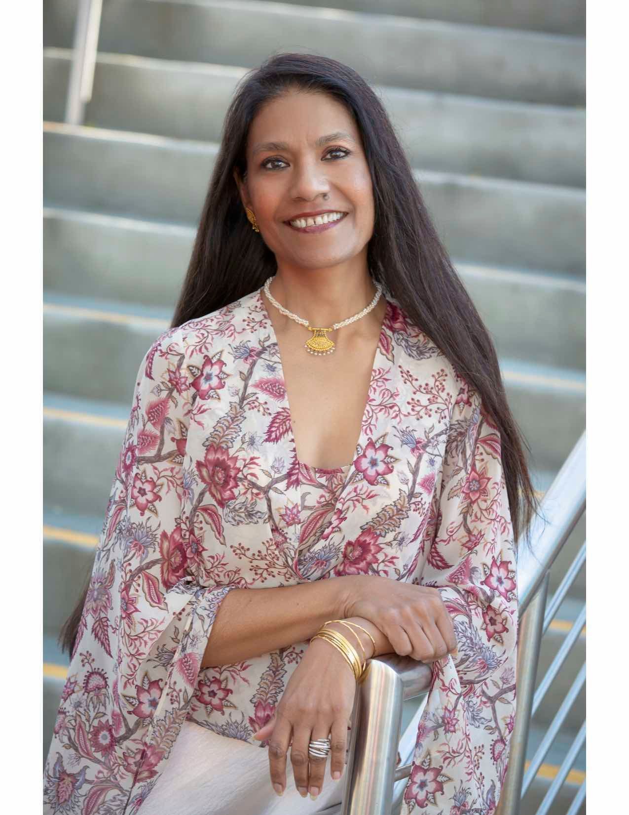 A woman is standing on a set of stairs wearing a floral shirt.