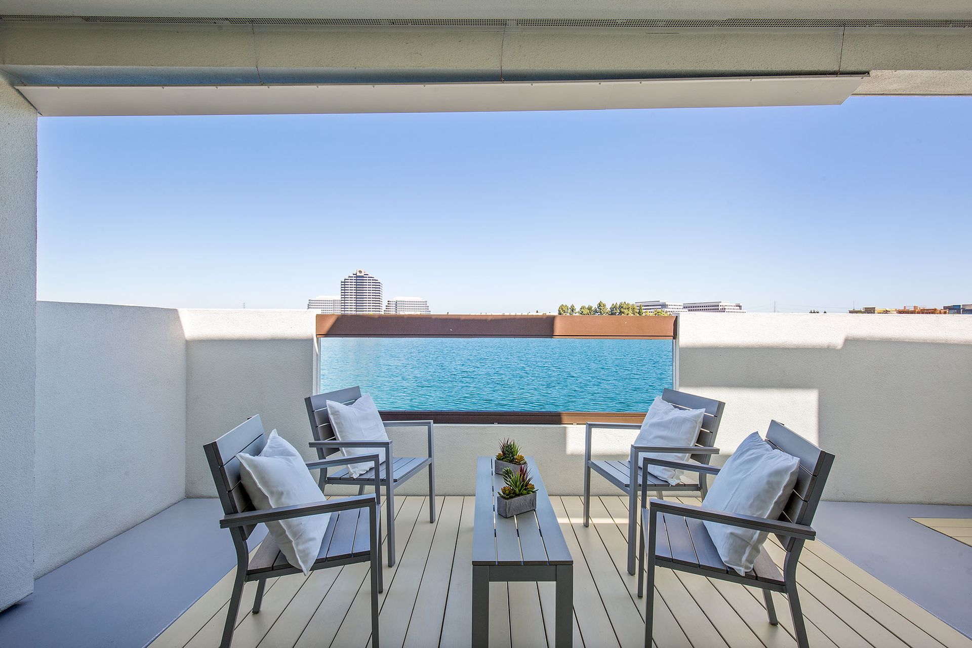 A balcony with chairs and a table overlooking a swimming pool.