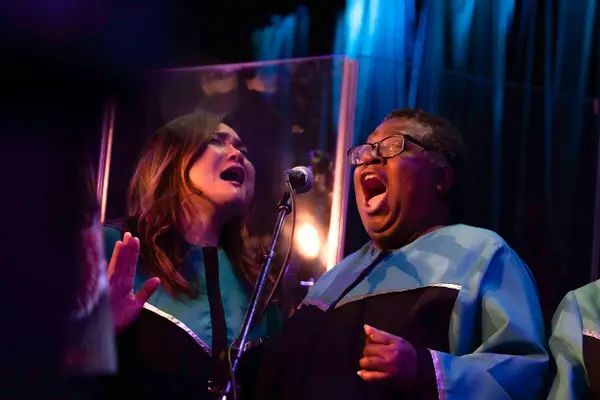 A group of women are singing into microphones on a stage.