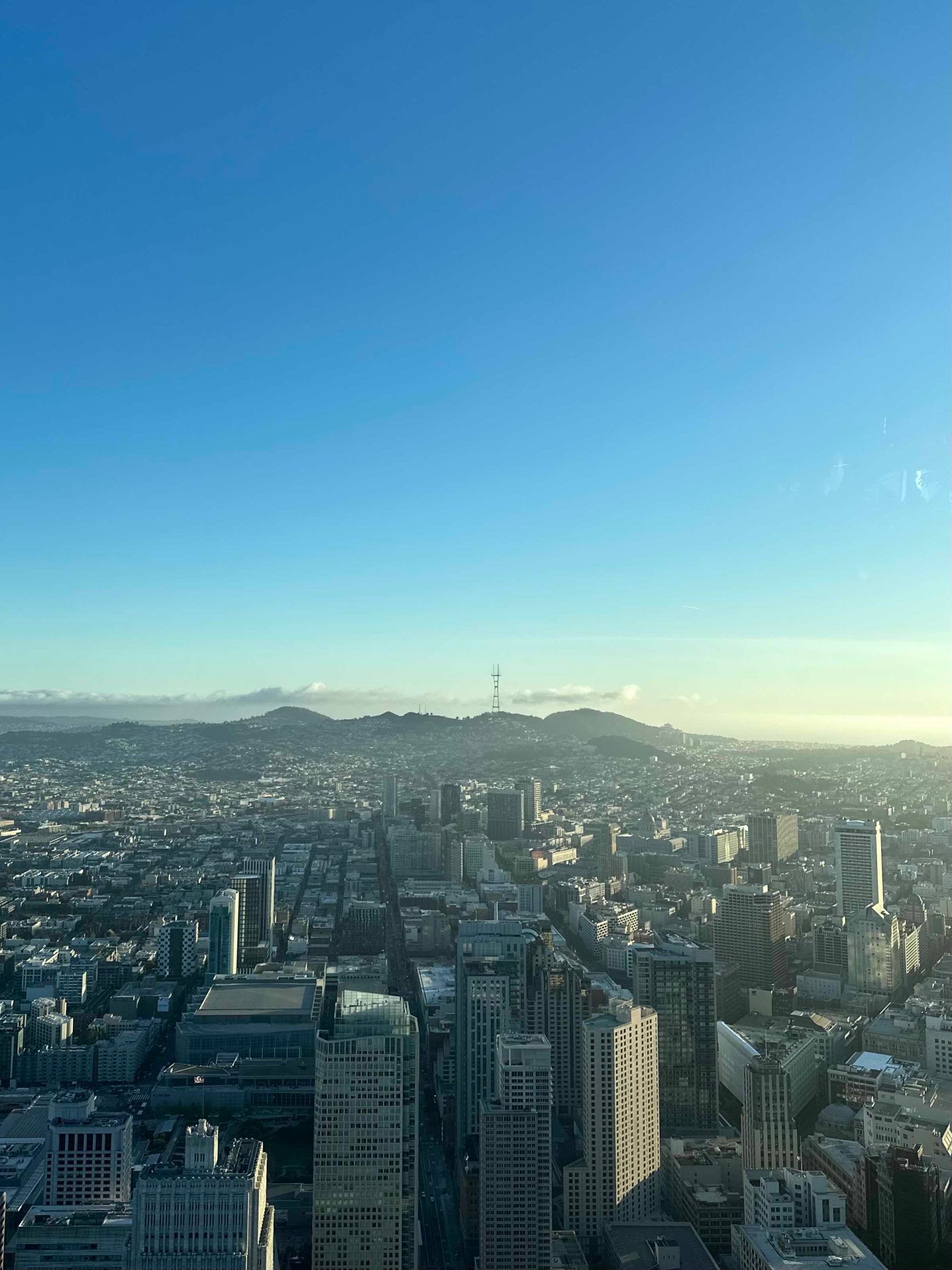 An aerial view of a city with a blue sky and mountains in the background.