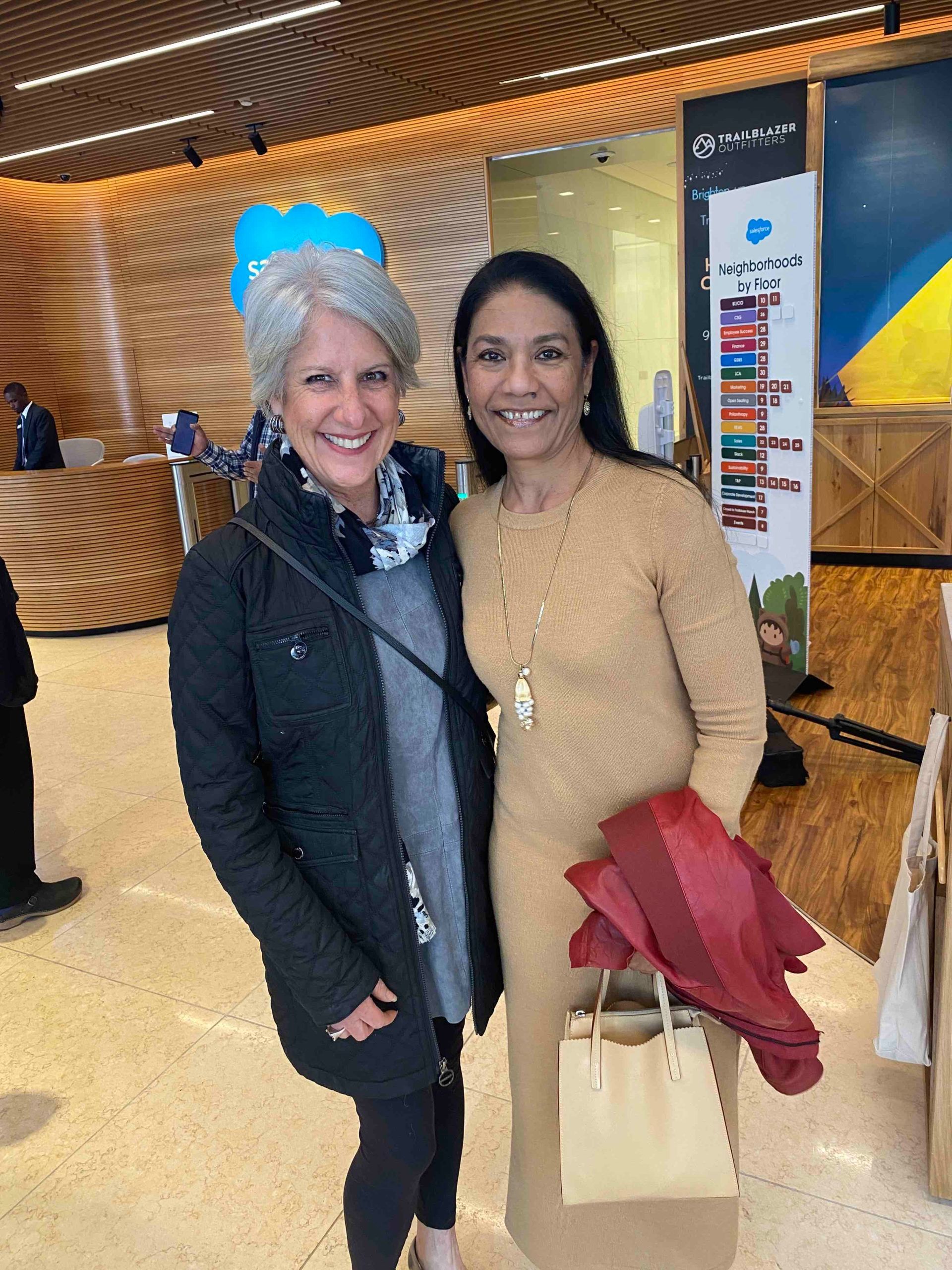 Two women are posing for a picture in a lobby