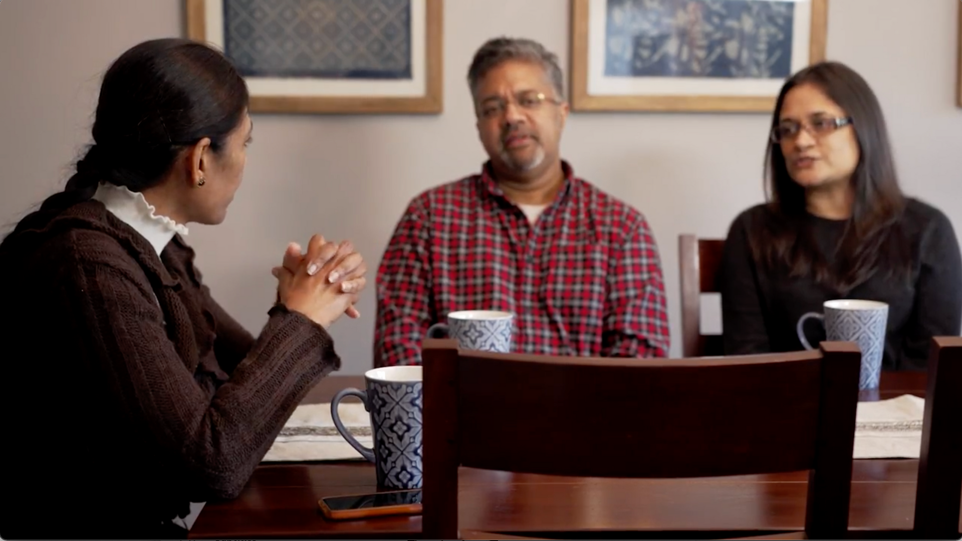 A man and two women are sitting at a table talking to each other.