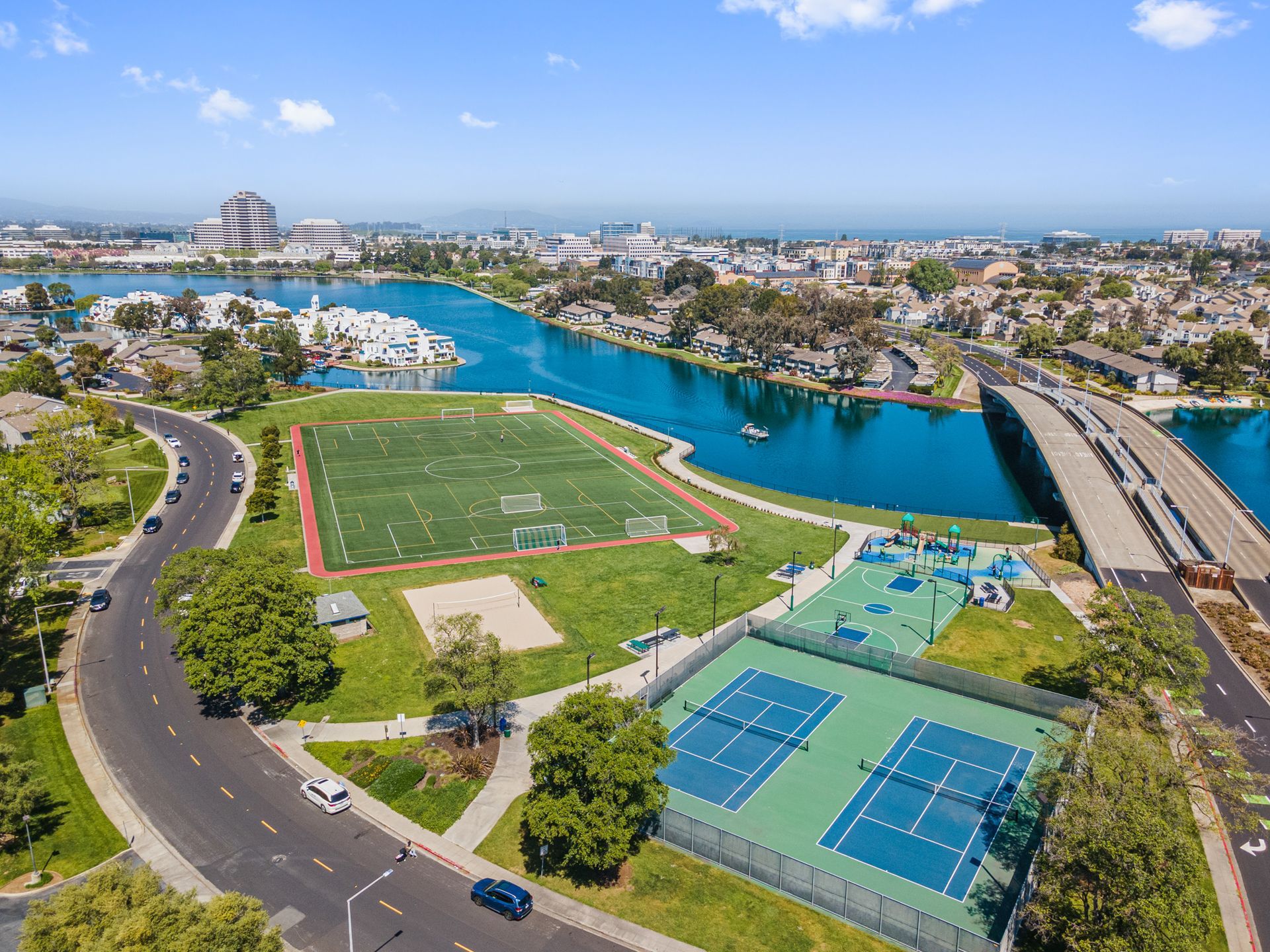 An aerial view of a tennis court in a park next to a river.