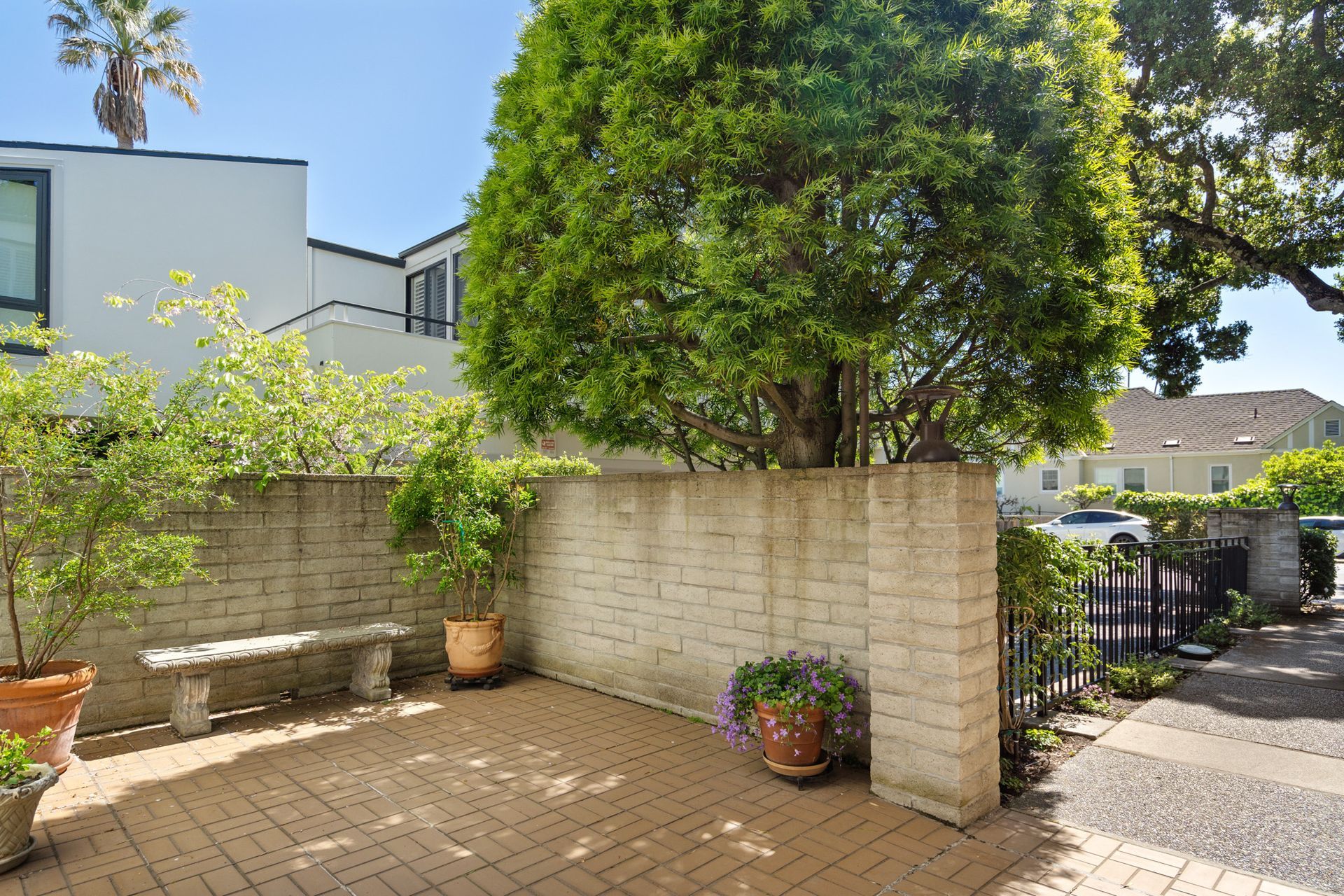 A brick wall with a bench and a tree in front of it