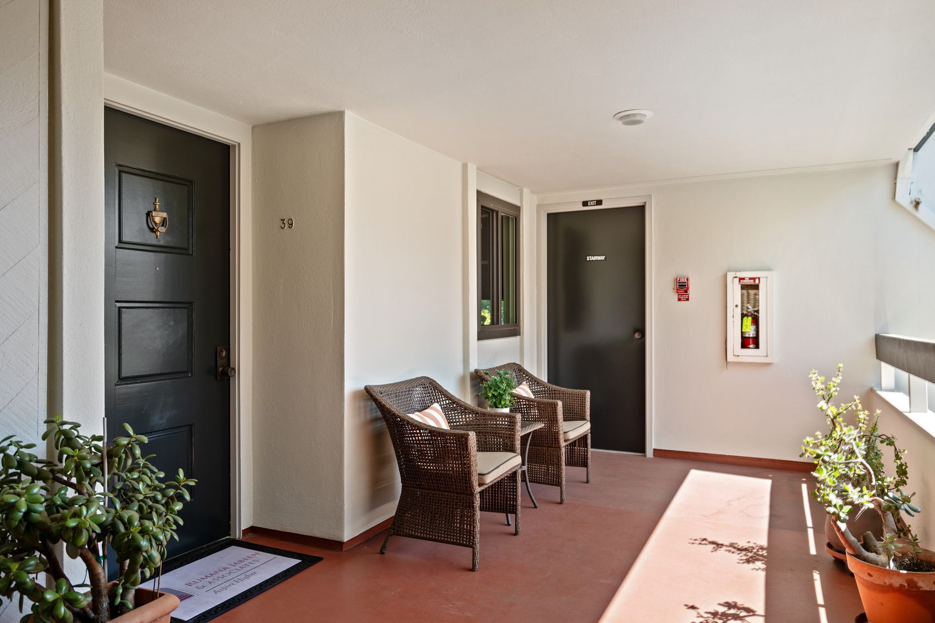 A hallway with wicker chairs and potted plants
