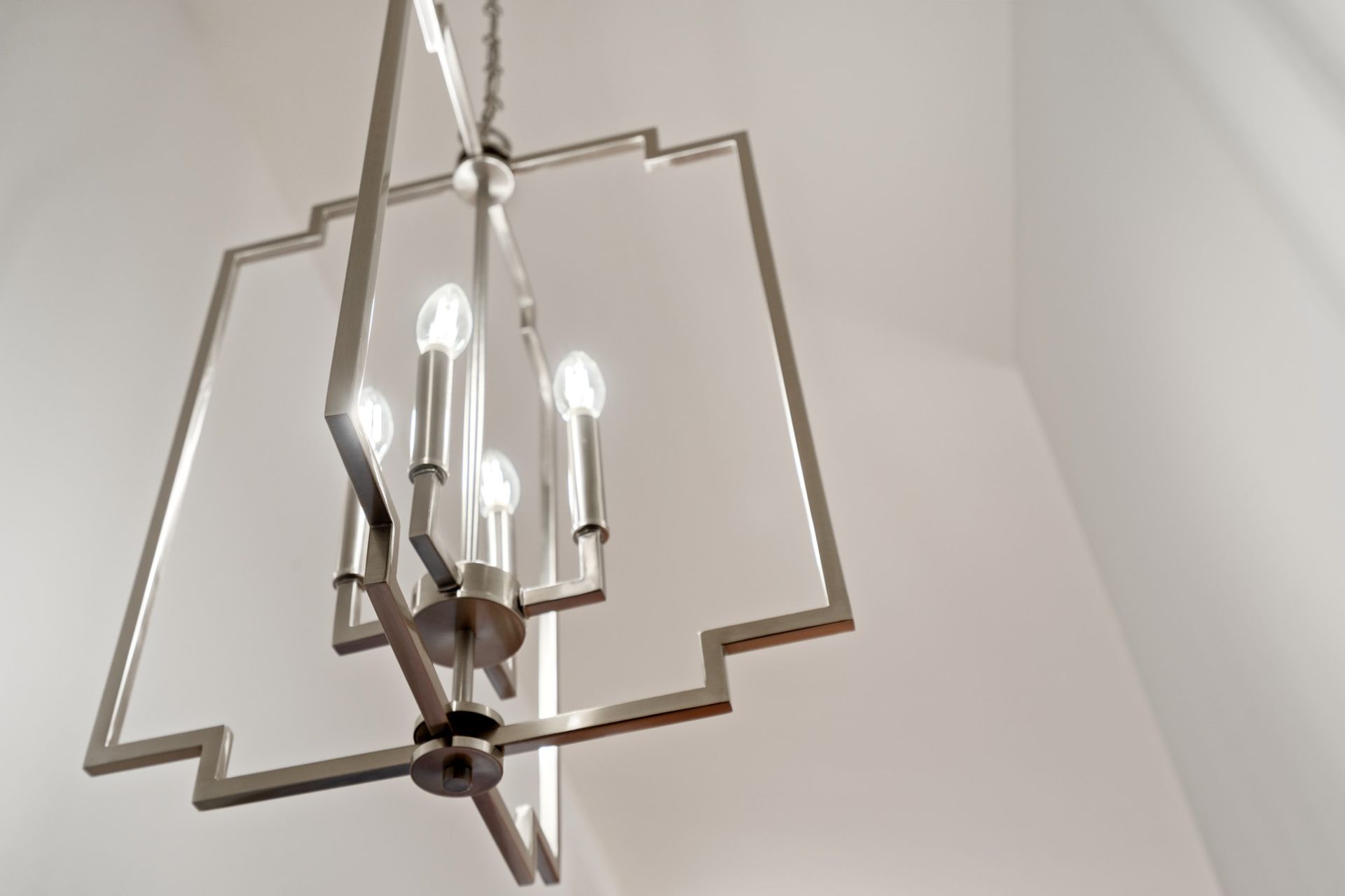 A silver chandelier is hanging from the ceiling in a room.