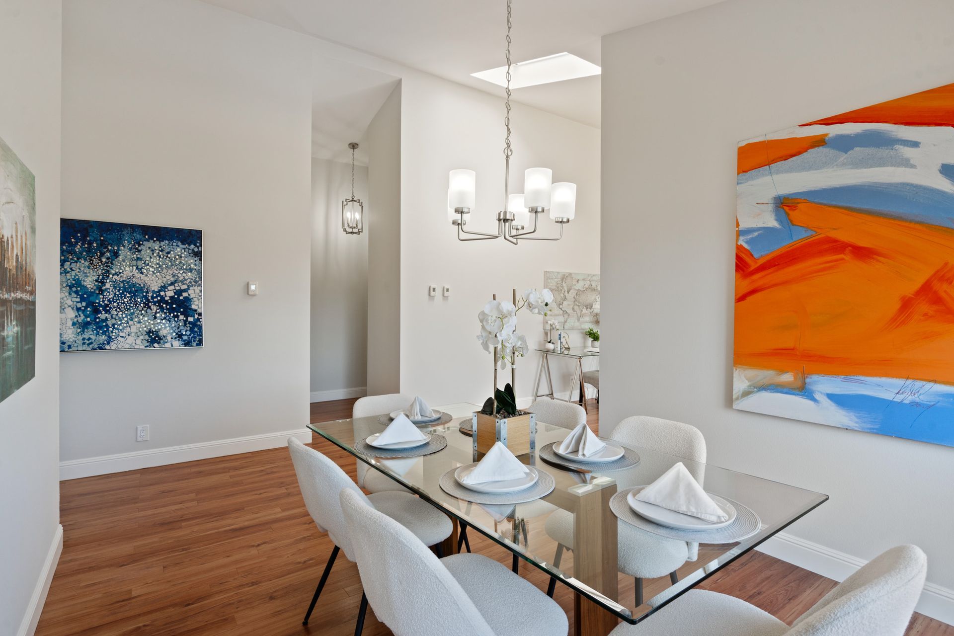 A dining room with a glass table and white chairs