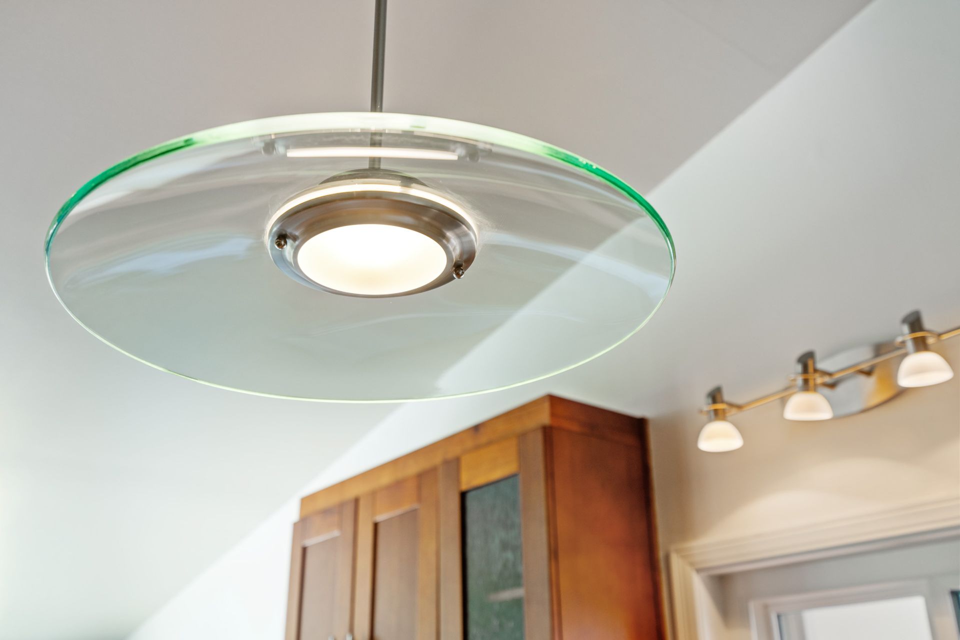 A glass pendant light is hanging from the ceiling in a kitchen.