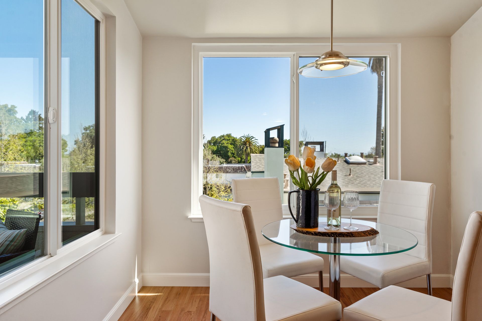 A dining room with a glass table and chairs and a large window.