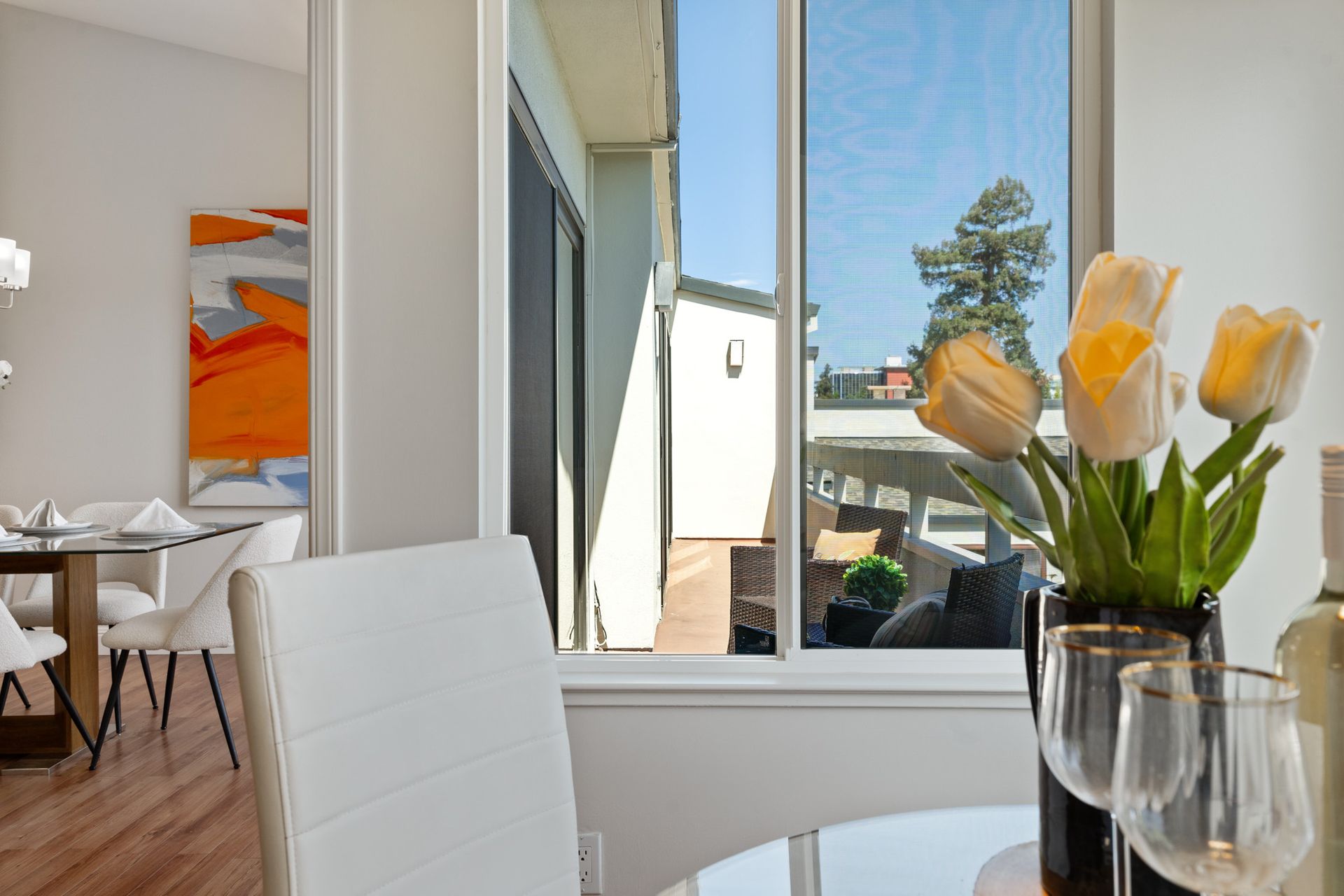 A dining room with a table and chairs and a vase of flowers