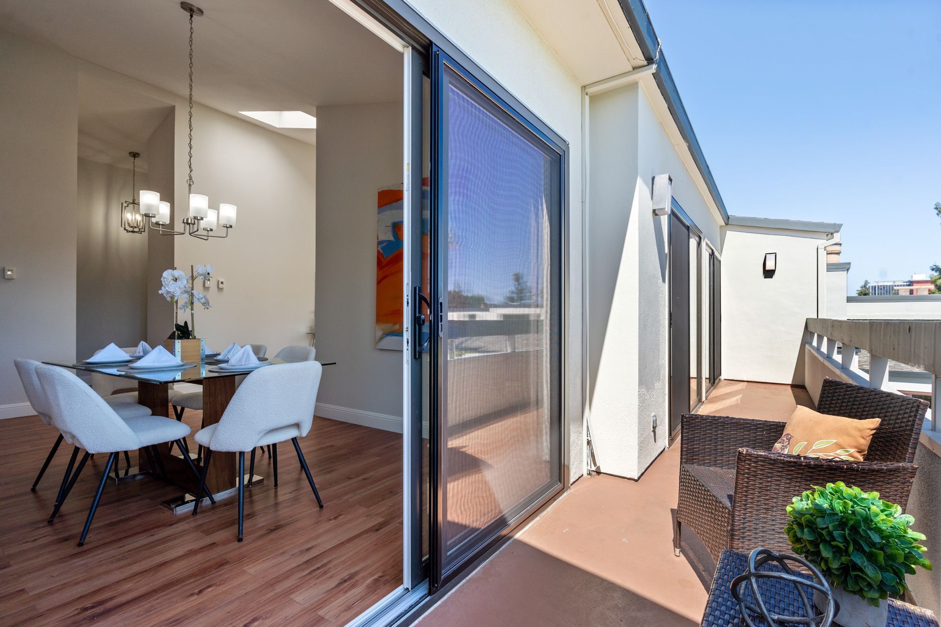 A dining room with a table and chairs and a balcony with a sliding glass door.