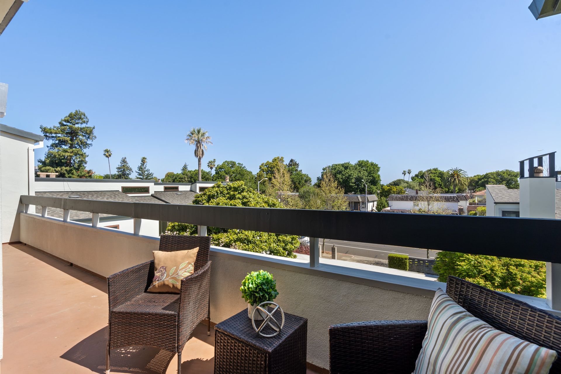 A balcony with two chairs and a table with a view of a city.