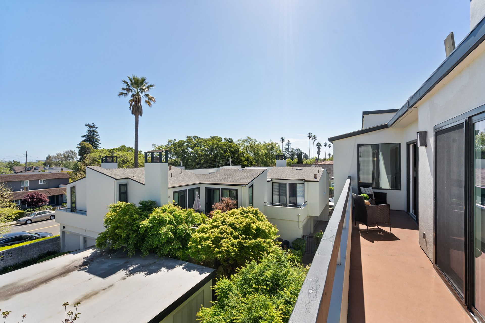 A balcony with a view of a city and a palm tree.