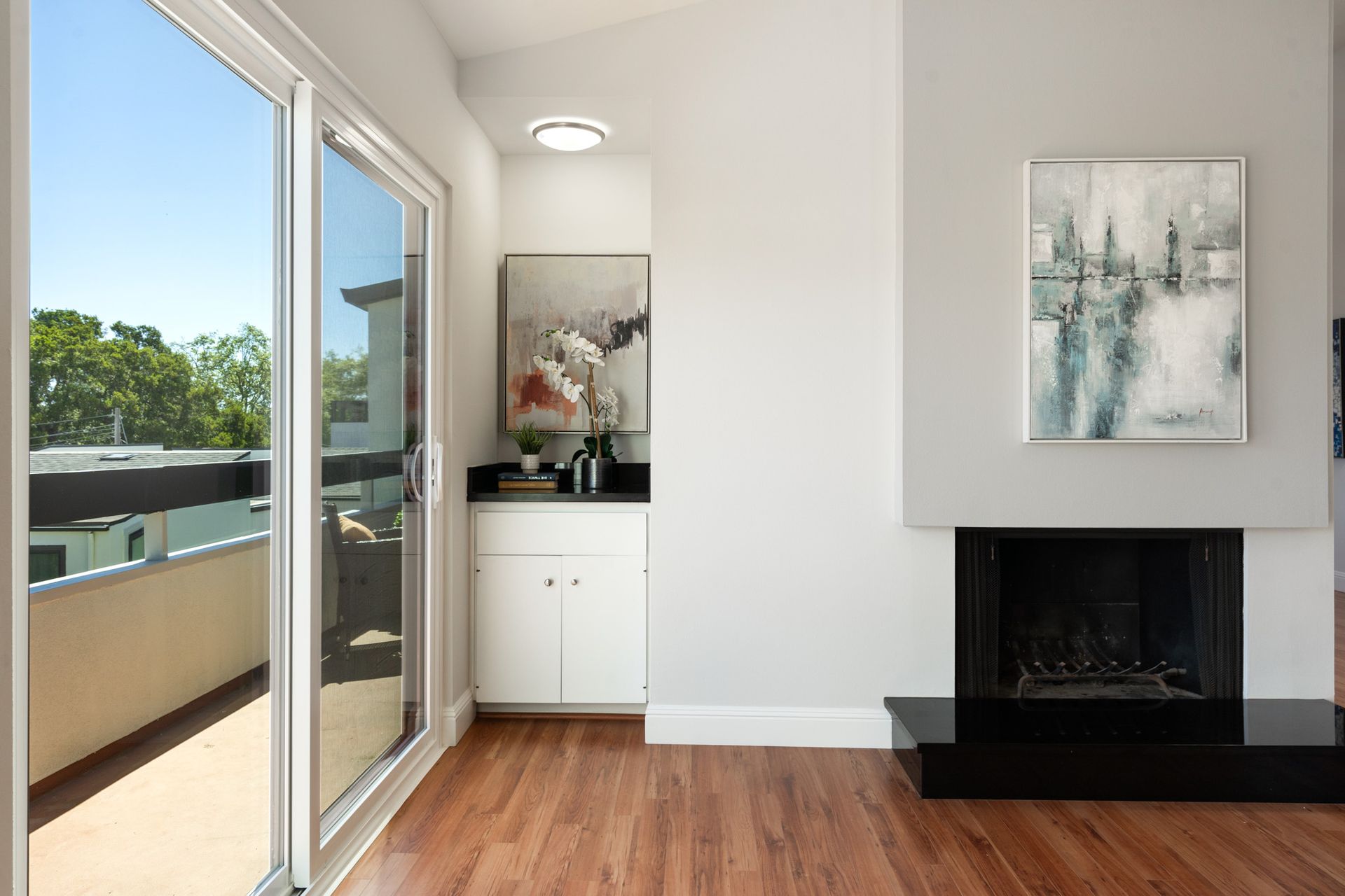 A living room with a fireplace , sliding glass doors and a painting on the wall.