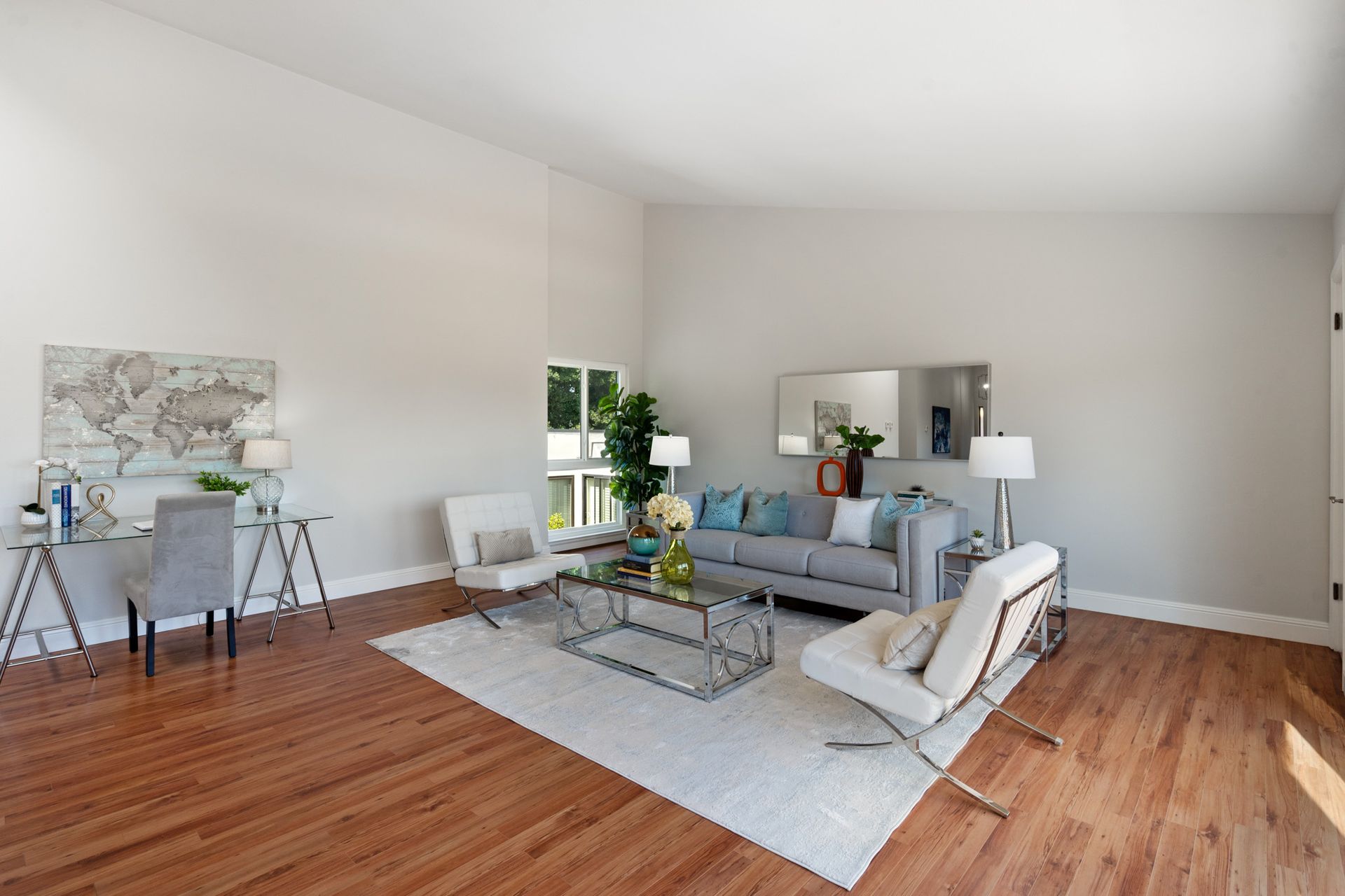 A living room with a couch , chairs , coffee table and desk.