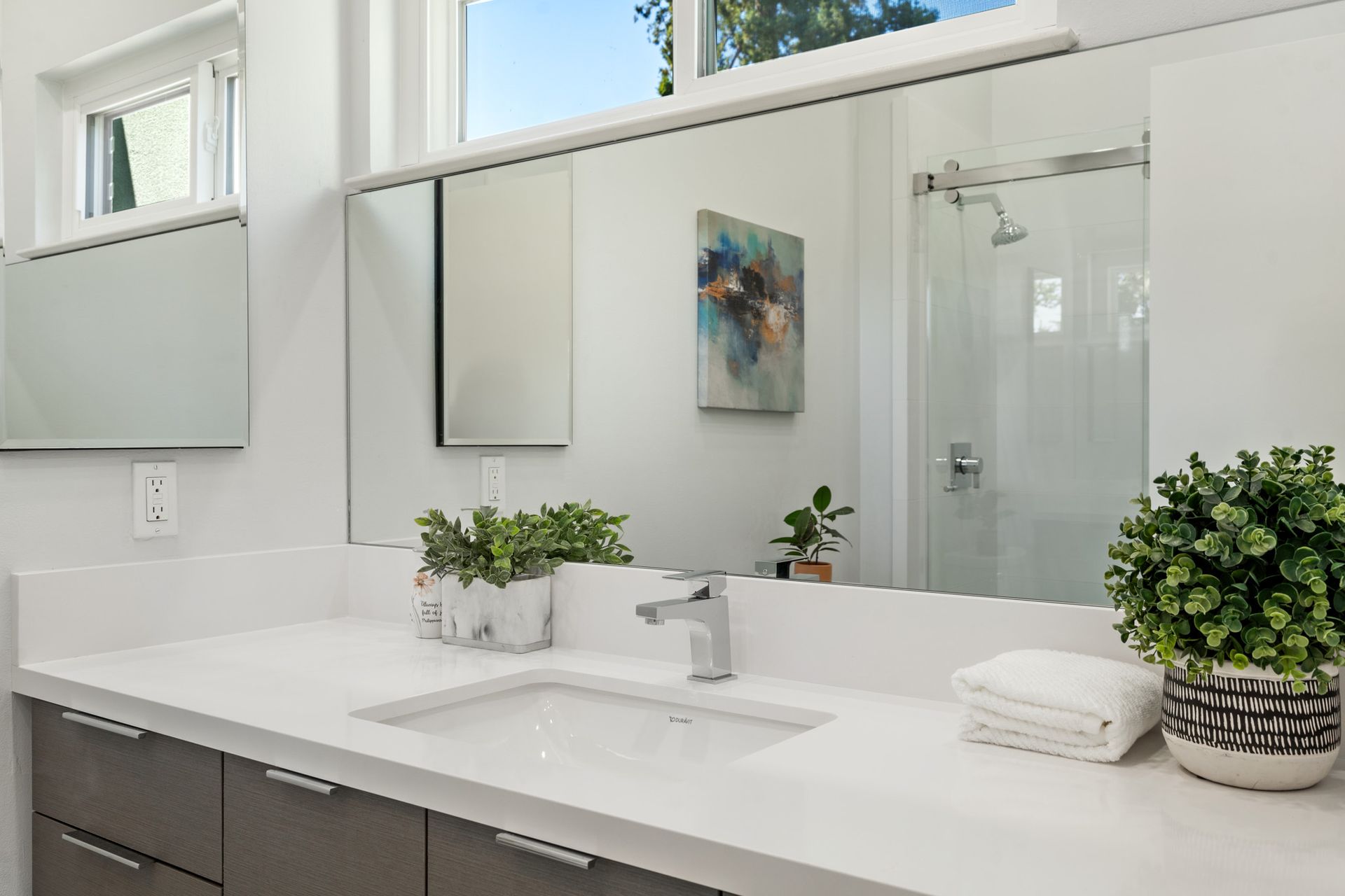 A bathroom with a sink , mirror and shower.