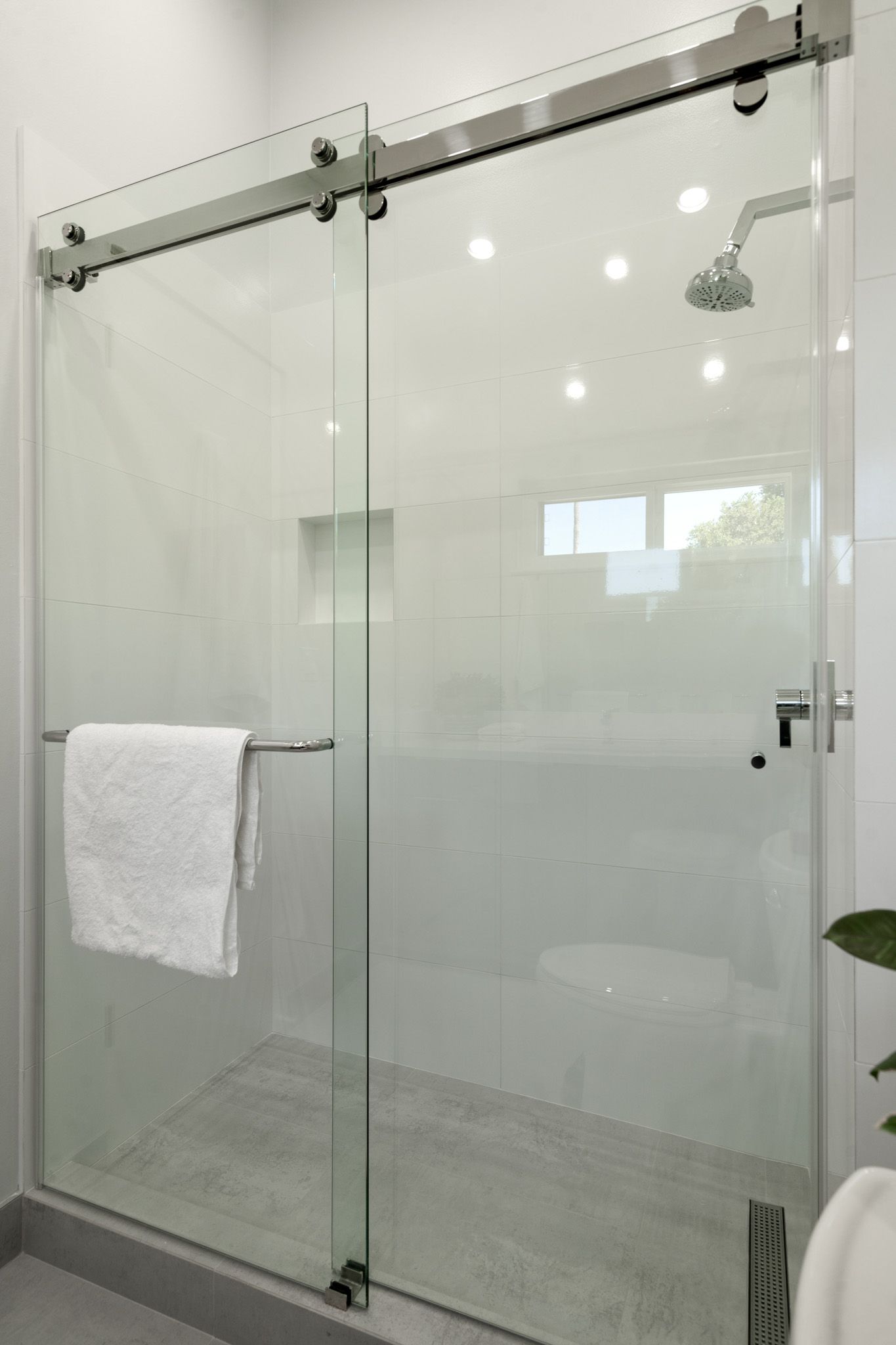 A bathroom with a sliding glass shower door and a towel hanging on the door.
