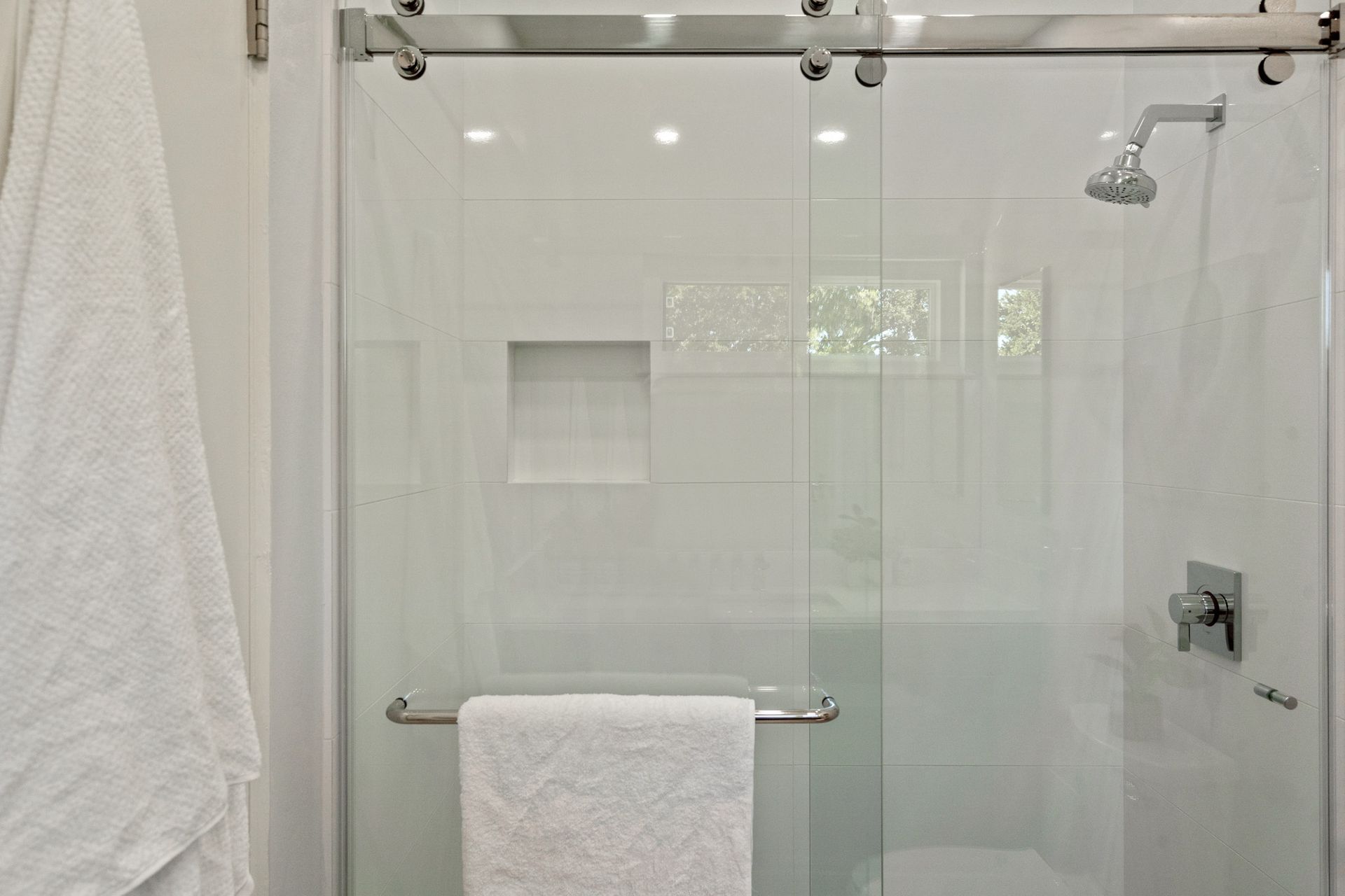 A bathroom with a sliding glass shower door and a towel rack.