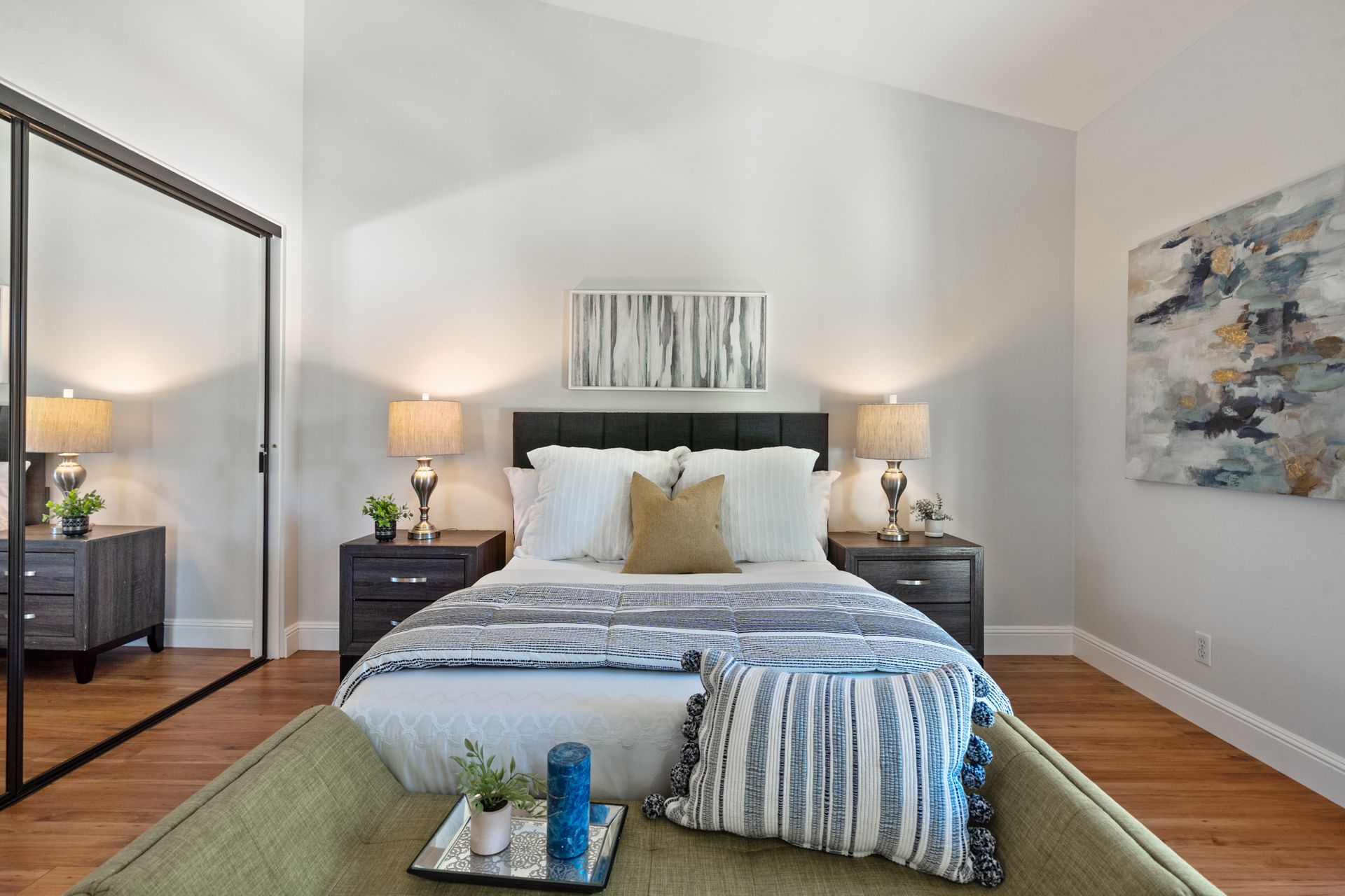 A bedroom with a bed , nightstands , lamps and a large mirror.