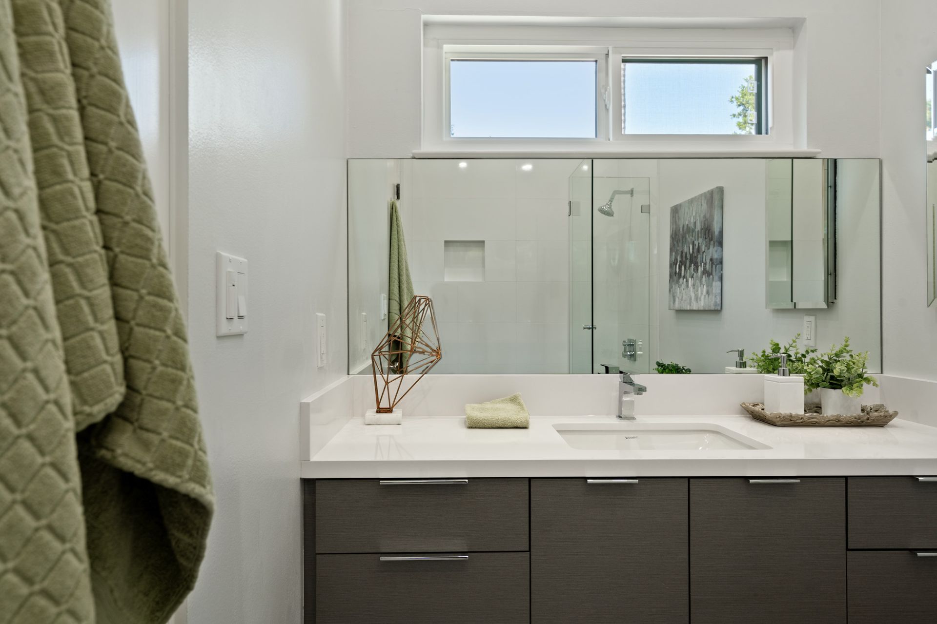 A bathroom with a sink , mirror and window.