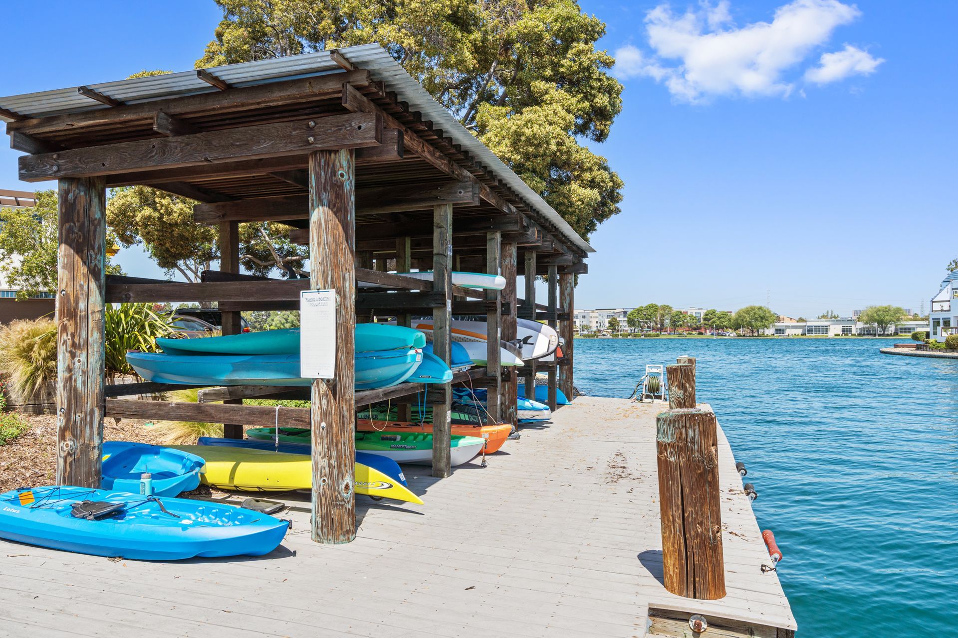 A row of kayaks are lined up on a dock next to a body of water.